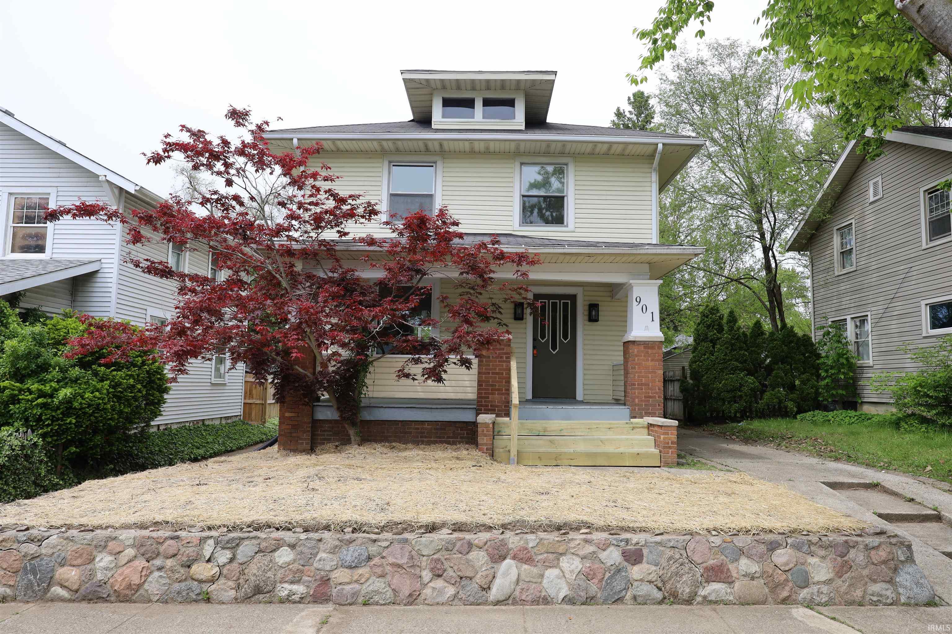Two-story residence featuring light-colored siding and a contrasting dark entry door