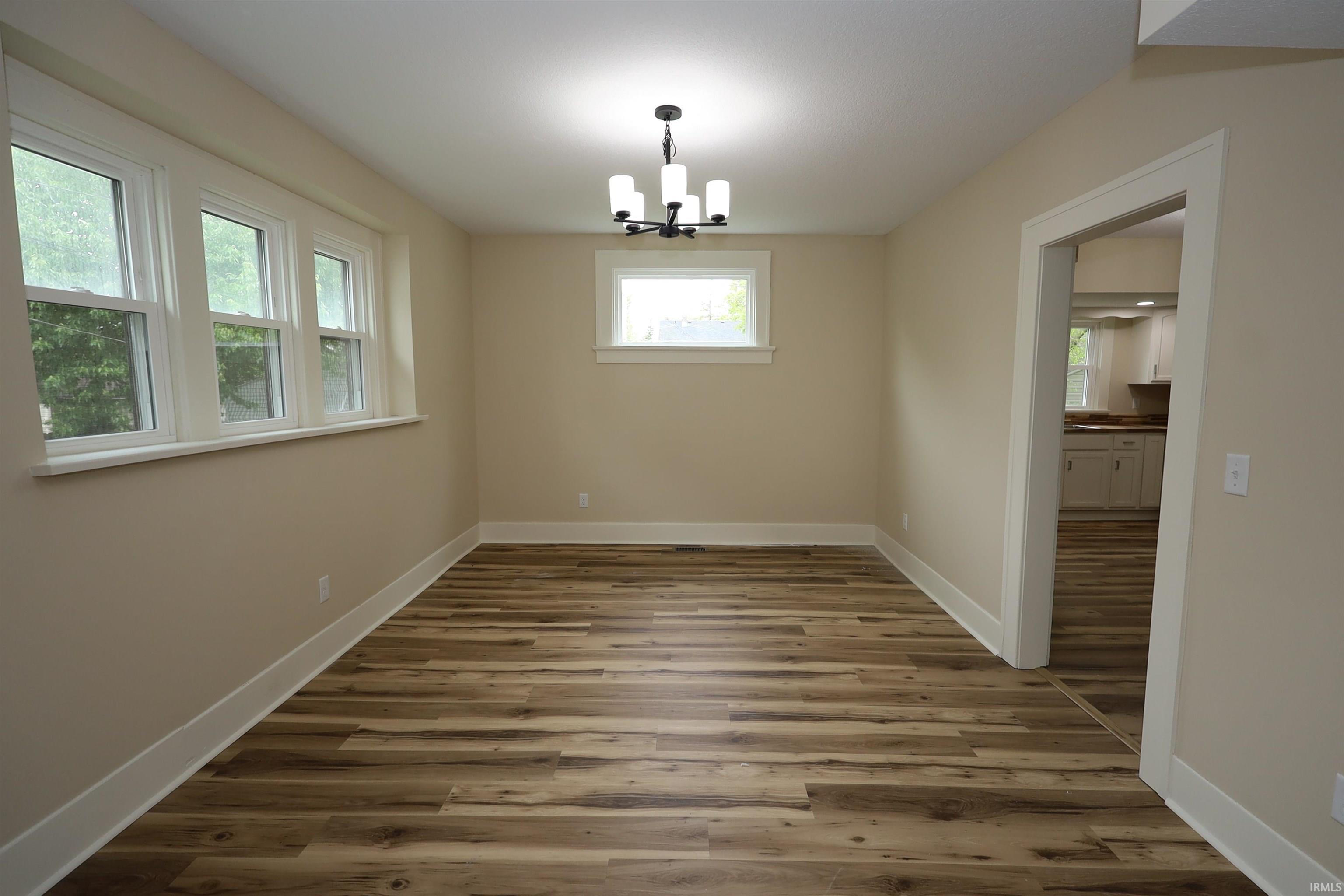 Spacious room featuring wood-finish flooring, light neutral wall tones, and white trim