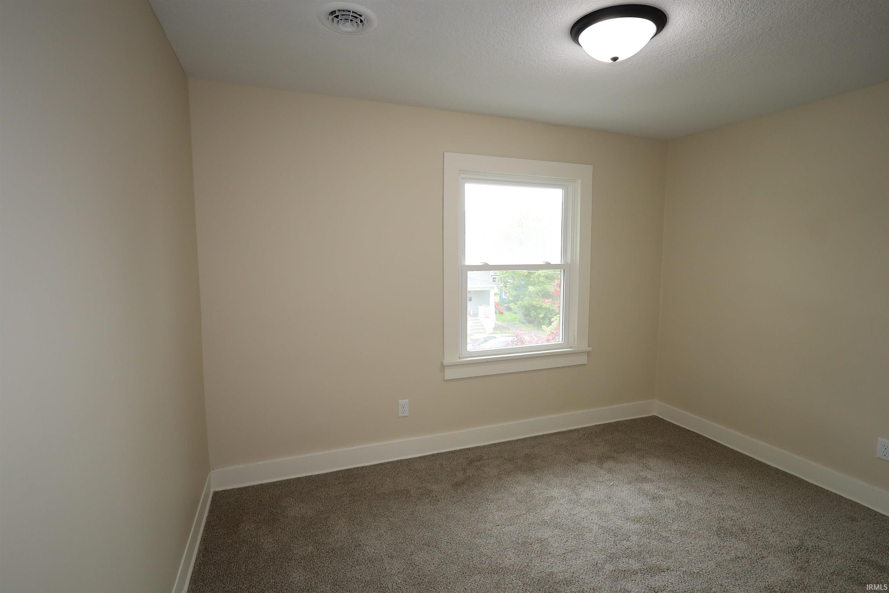 Room featuring a single-hung window with white trim, neutral tone walls, and gray carpet flooring
