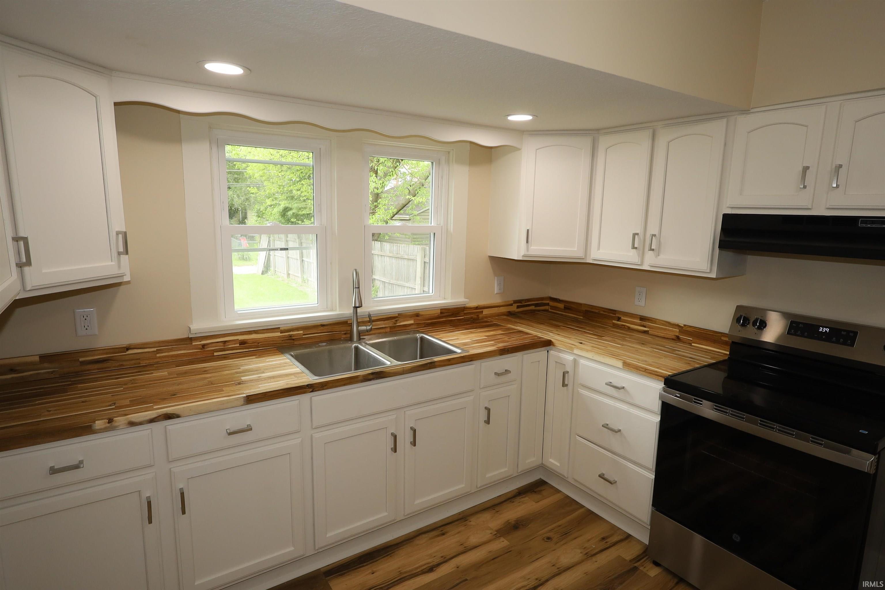 Kitchen featuring white cabinetry, light wood-finish countertops, and stainless steel appliances
