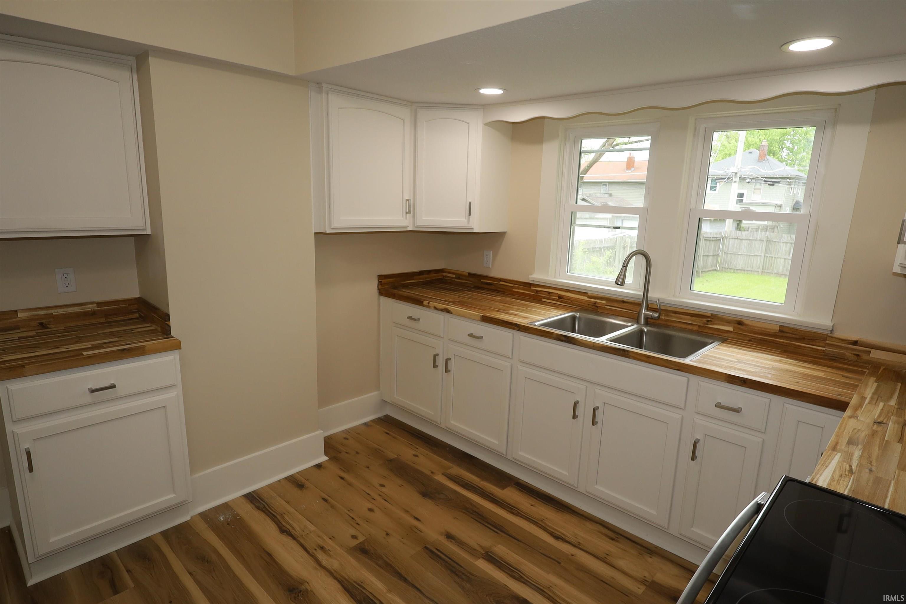 Kitchen featuring white cabinetry, wood-finish countertops, and wood-finish flooring