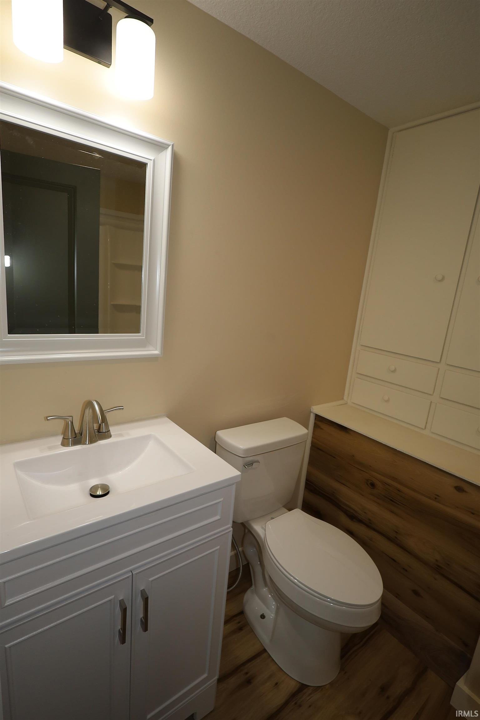 Bathroom featuring a white vanity with paneling detail and brushed nickel hardware, a white integrated sink, and a brushed nickel faucet