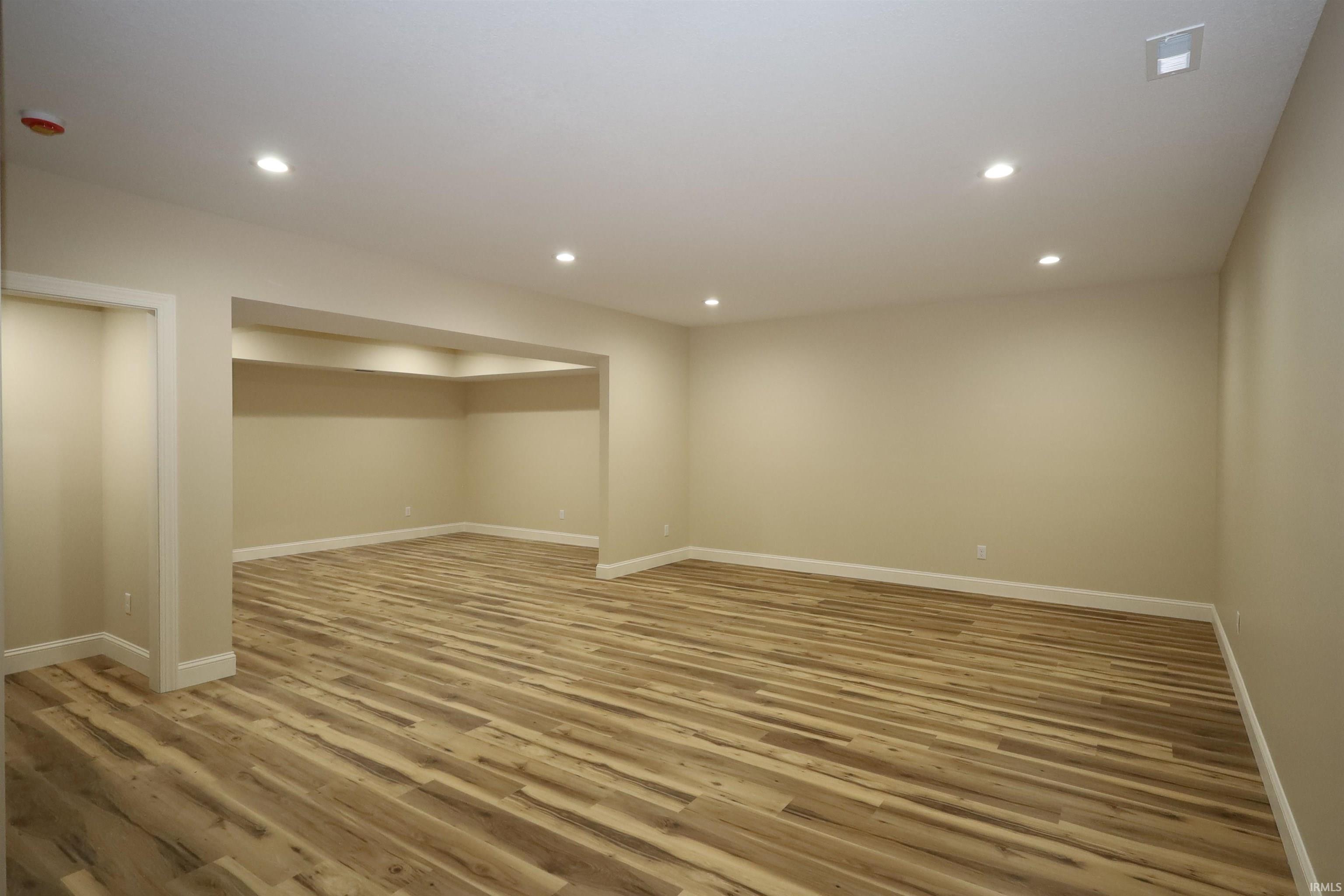Spacious room featuring wood-finish flooring, recessed lighting, and neutral wall paint