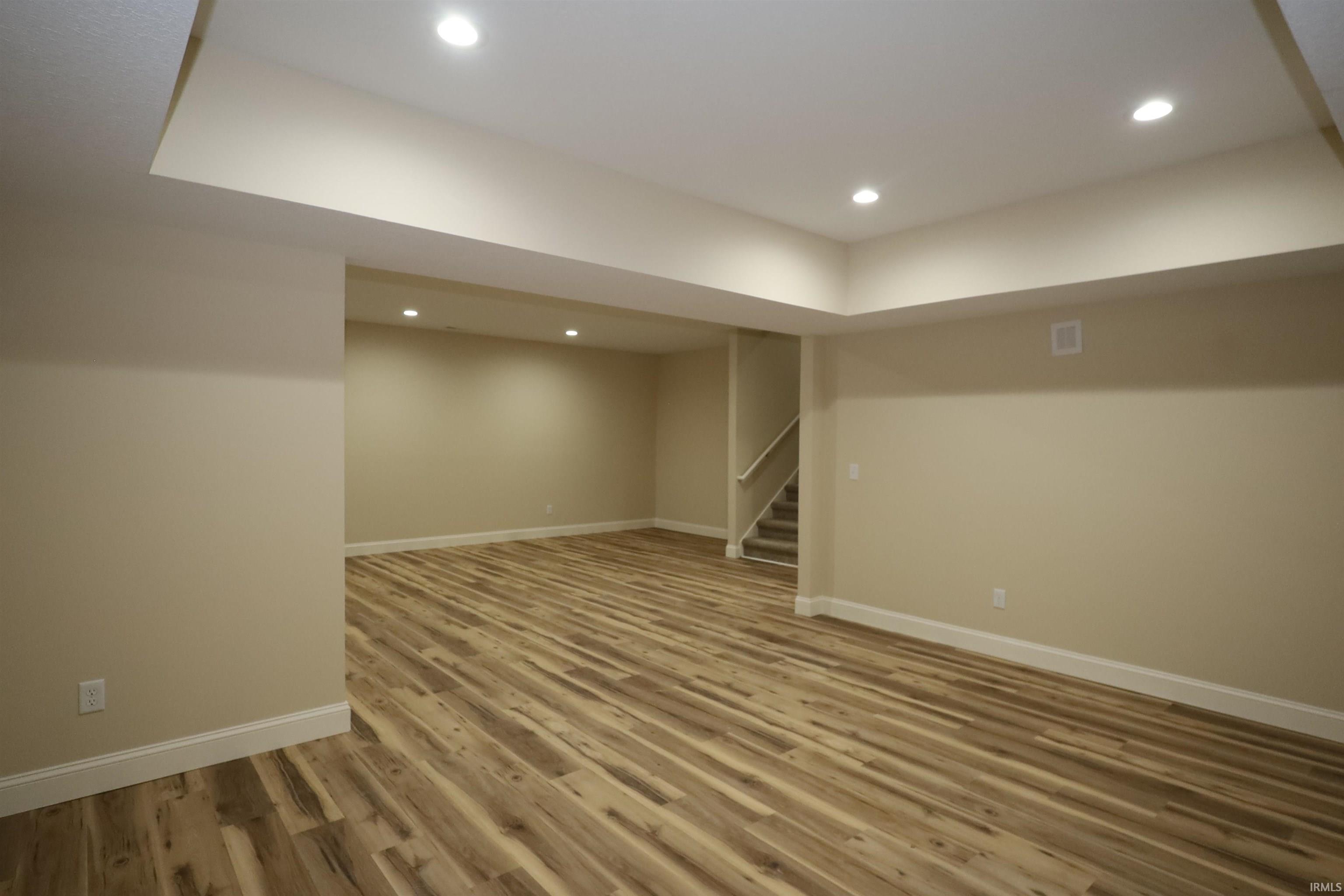 Expansive finished lower level featuring wood-finish flooring, recessed lighting, neutral wall tones, and white trim