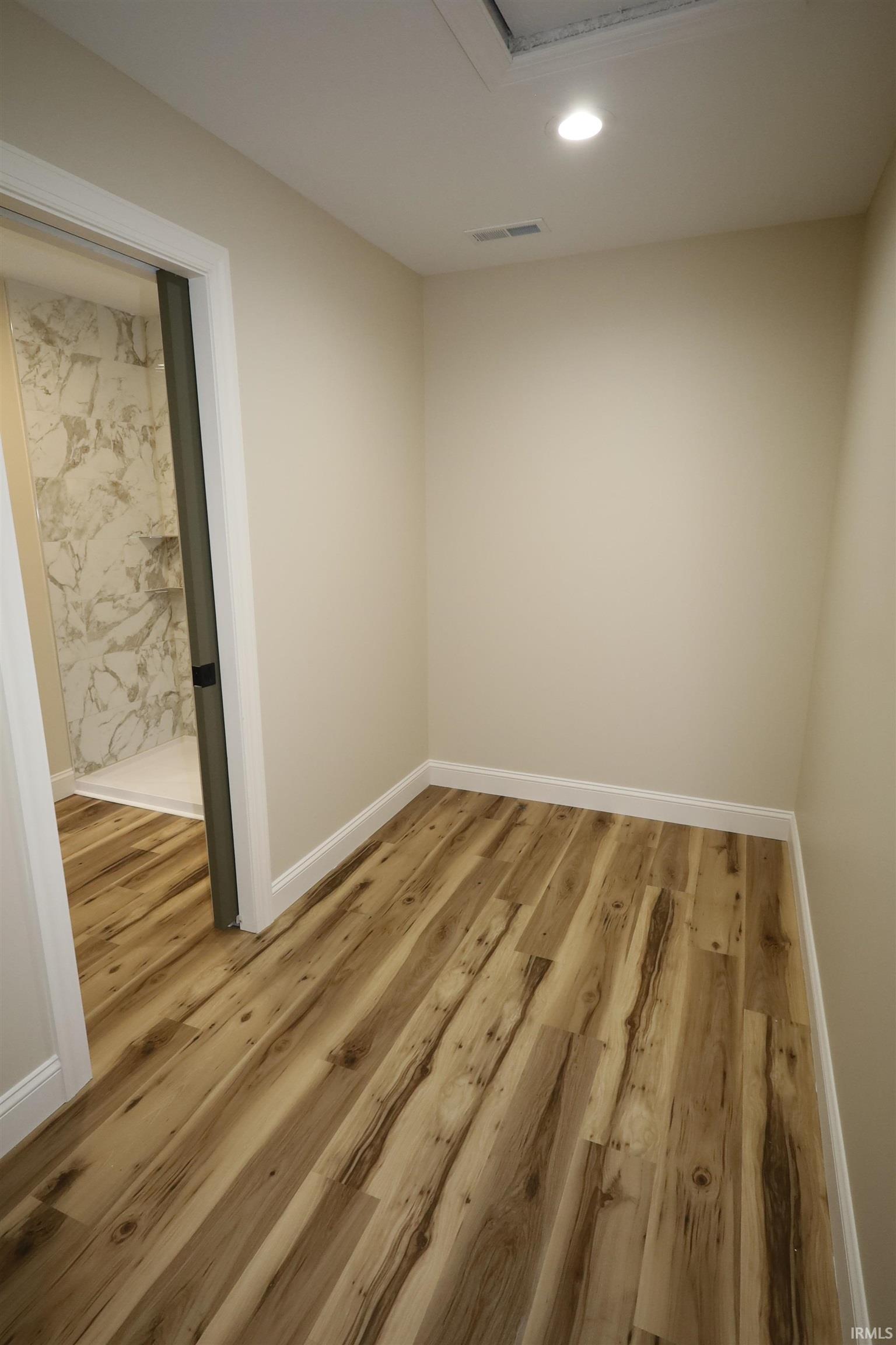 Neutral wall paint, wood-finish flooring, white baseboards, and recessed lighting