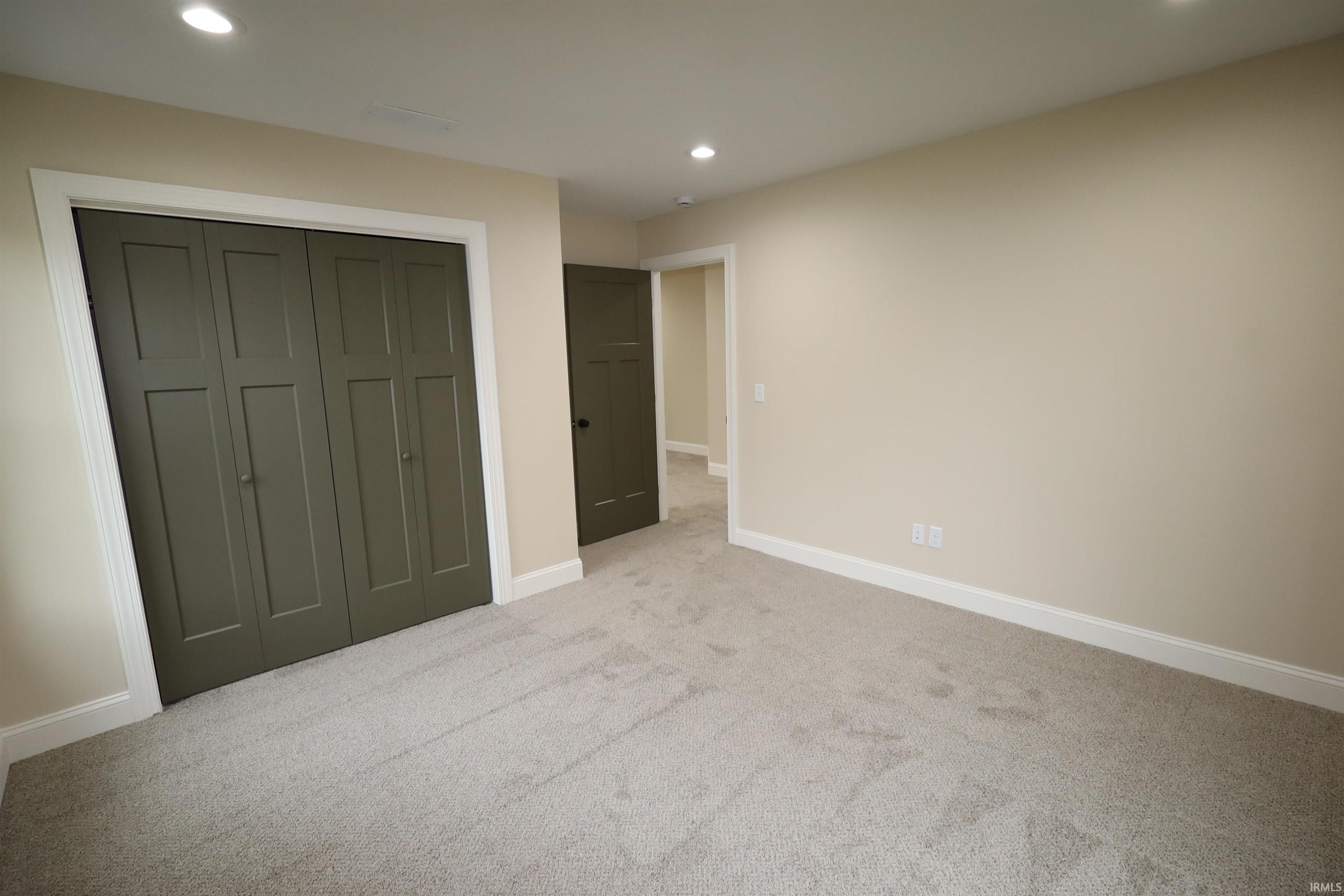 Neutral-toned carpeting extends throughout this room, featuring recessed lighting and light cream wall finishes