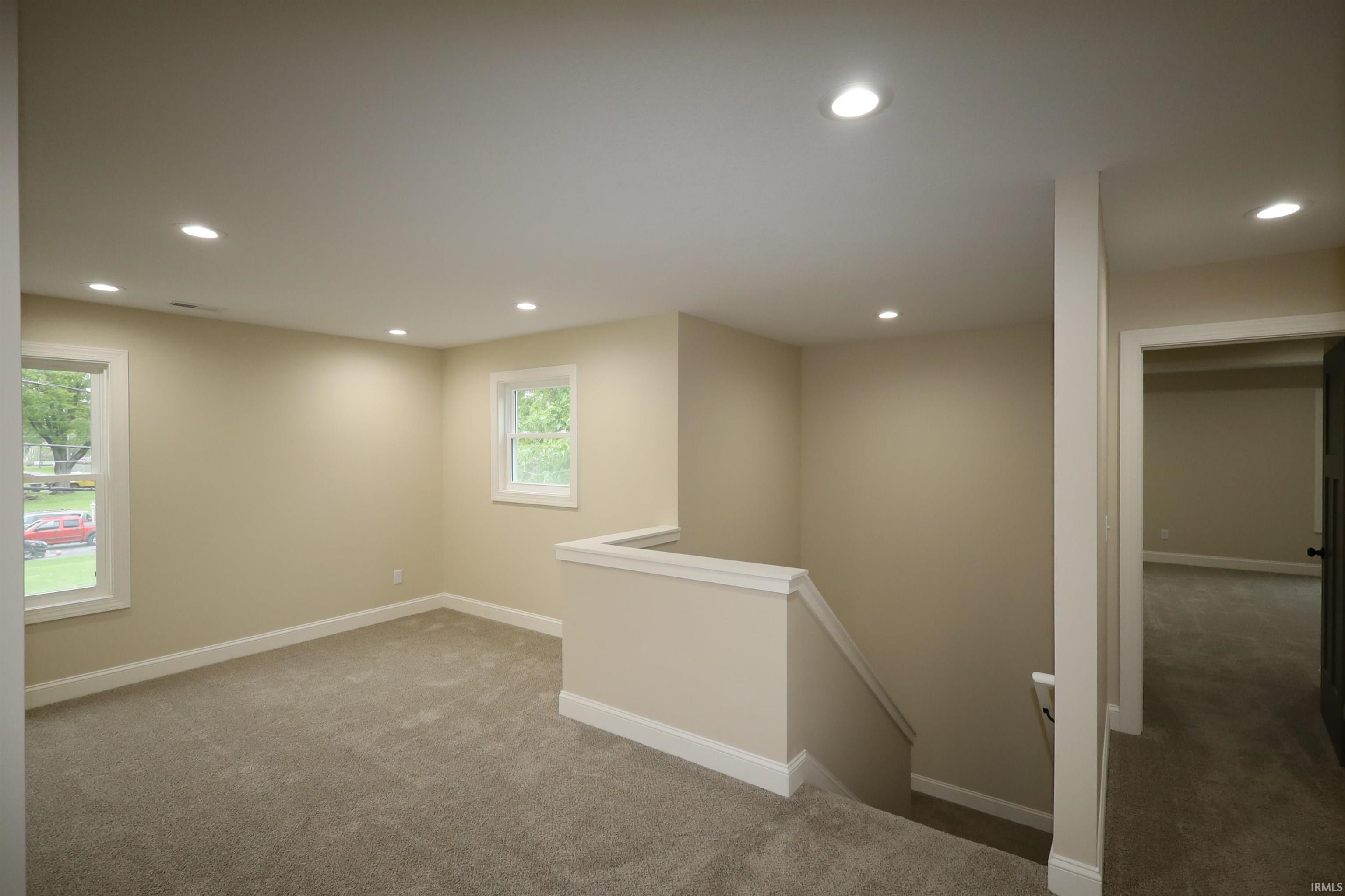 Carpeted living area featuring recessed lighting, painted walls, white trim, and two windows providing natural illumination