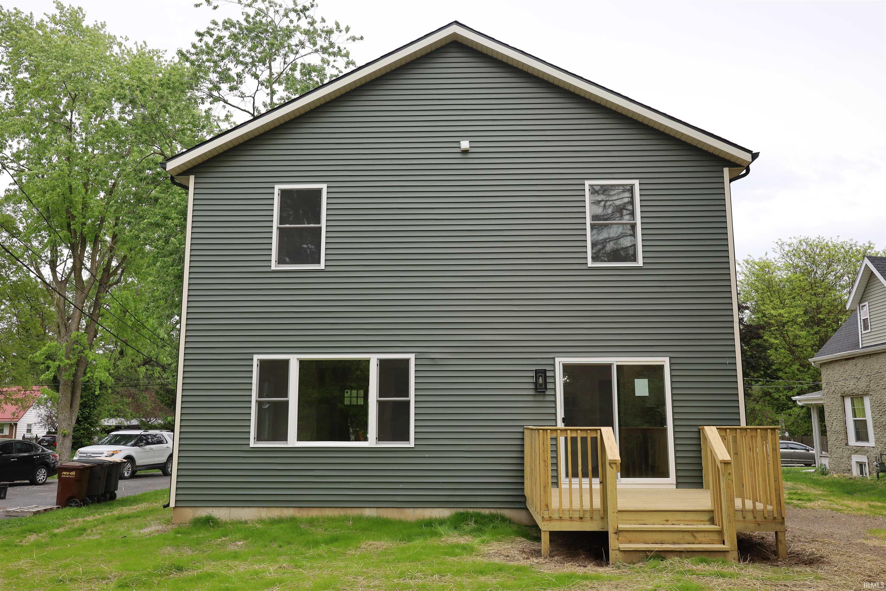 Rear exterior featuring dark gray horizontal siding, white trim, and a newly constructed wood deck