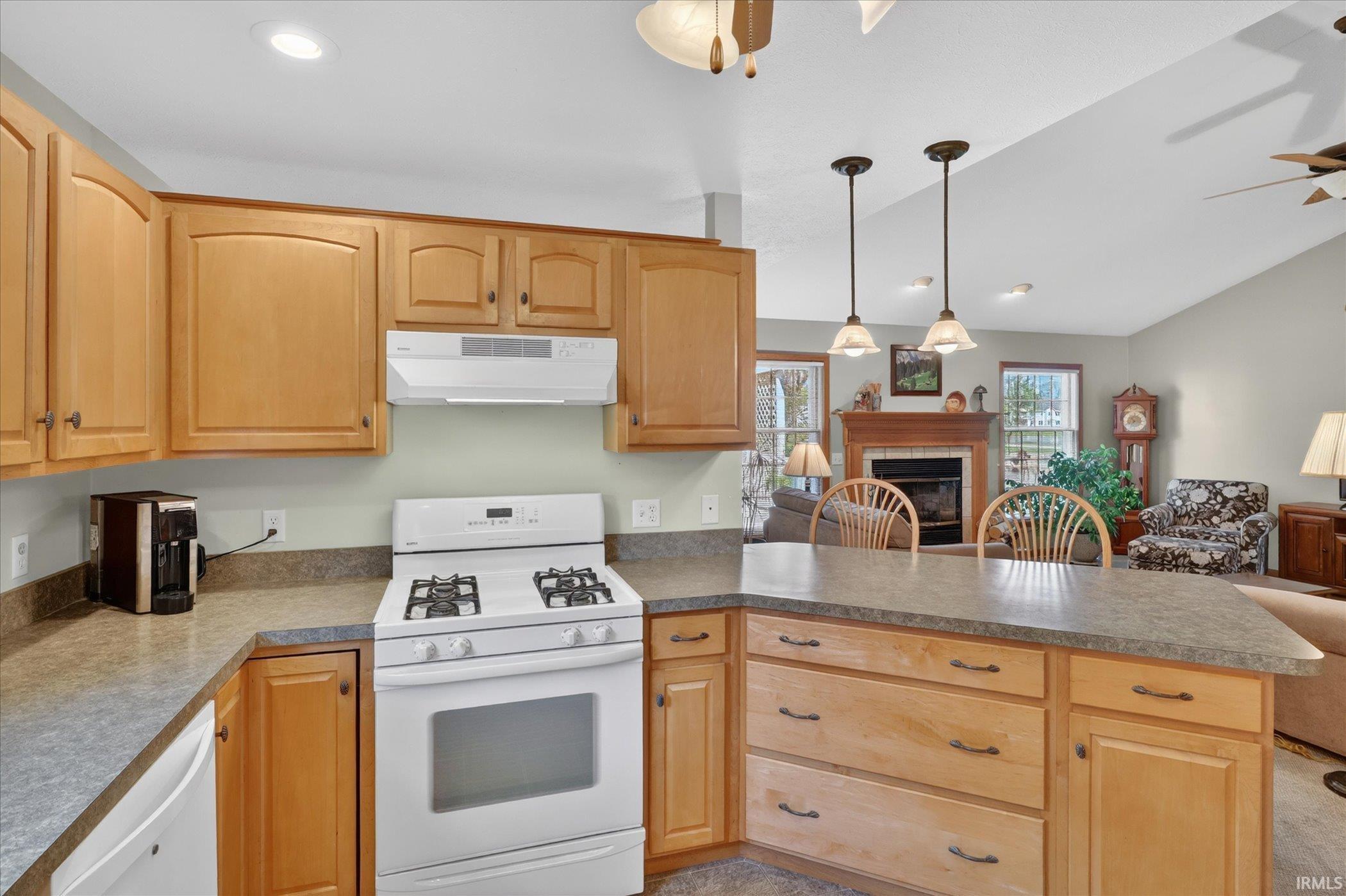 Kitchen featuring light wood cabinetry, gray countertops, a built-in range with overhead ventilation, recessed lighting, and pendant lighting over a peninsula