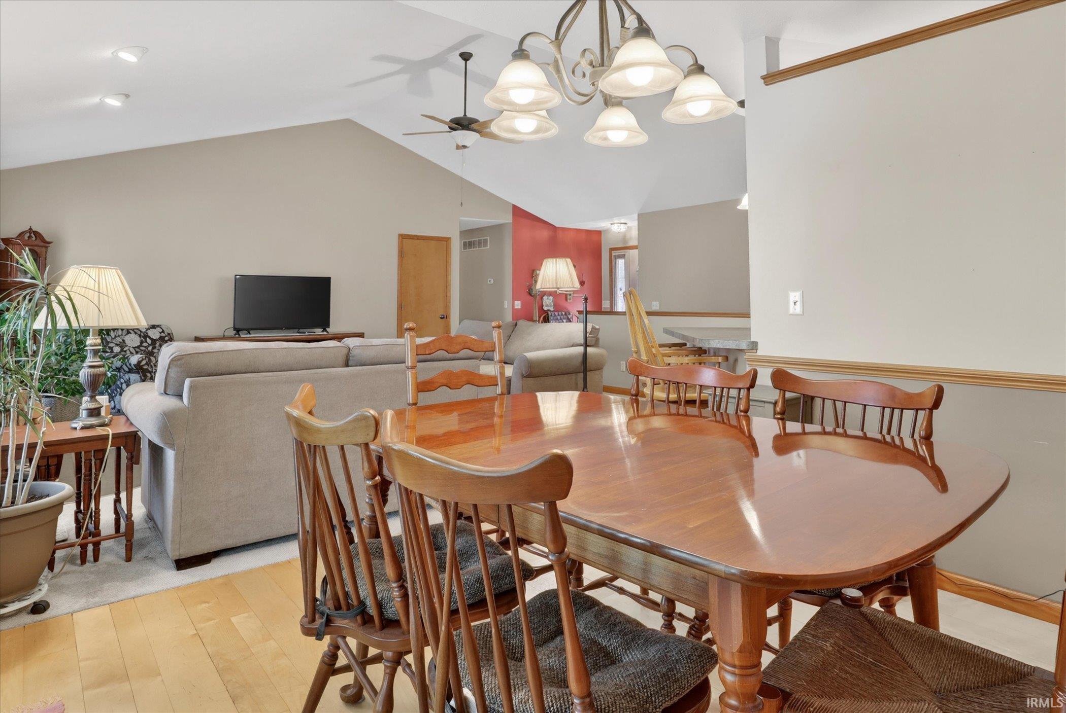 Dining area featuring wood-finish flooring, a vaulted ceiling, and a multi-light chandelier