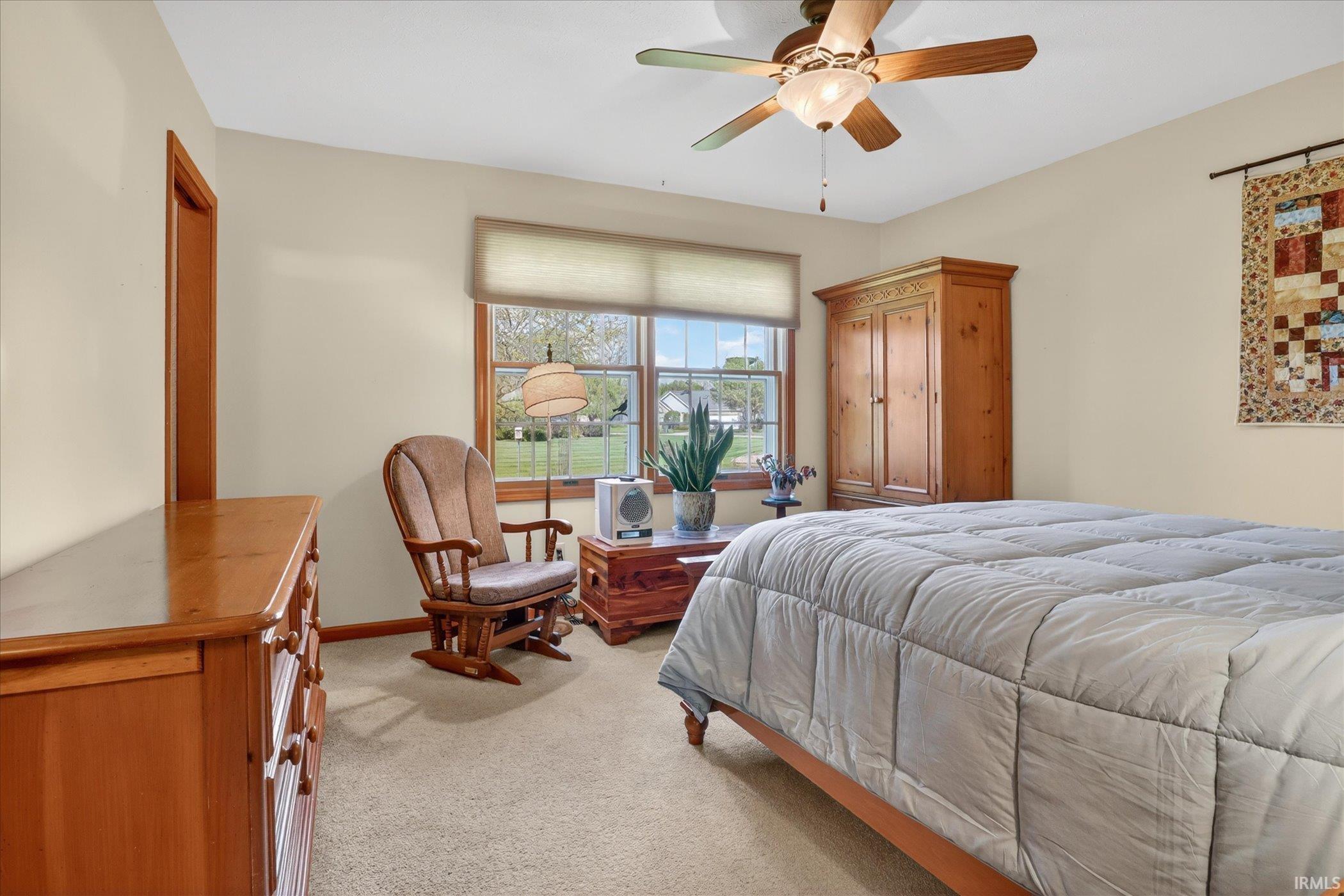 Carpeted room featuring a window with blinds, wood trim, a ceiling fan with integrated lighting, and neutral-toned walls