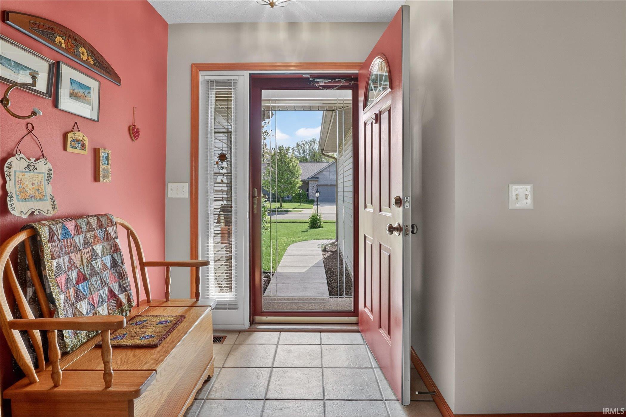 Entryway featuring light-toned tile flooring, a red paneled front door with an arched glass insert, and a sidelight with blinds