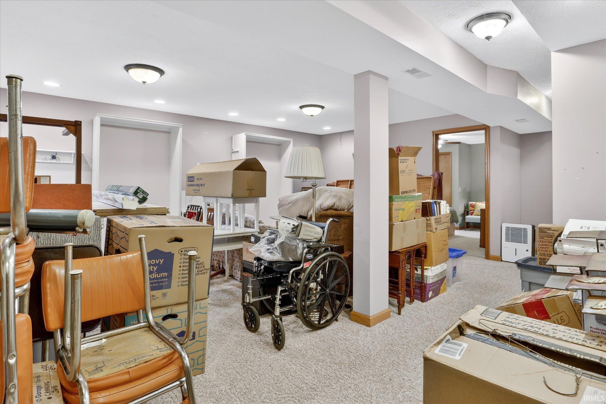 Carpeted basement with recessed ceiling lights and structural support columns