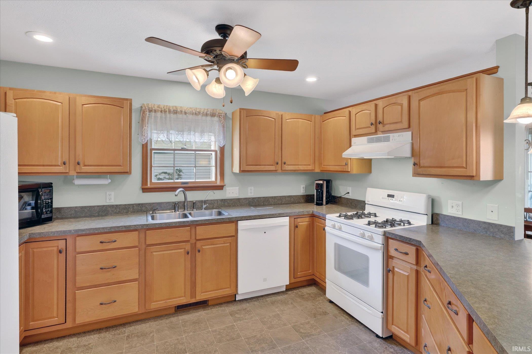Kitchen featuring light wood cabinetry, a dual basin stainless steel sink, a white gas range, a white dishwasher, and recessed lighting