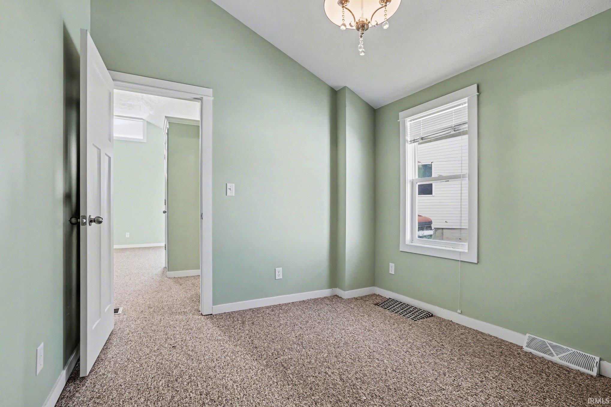 Empty room featuring lofted ceiling and light carpet