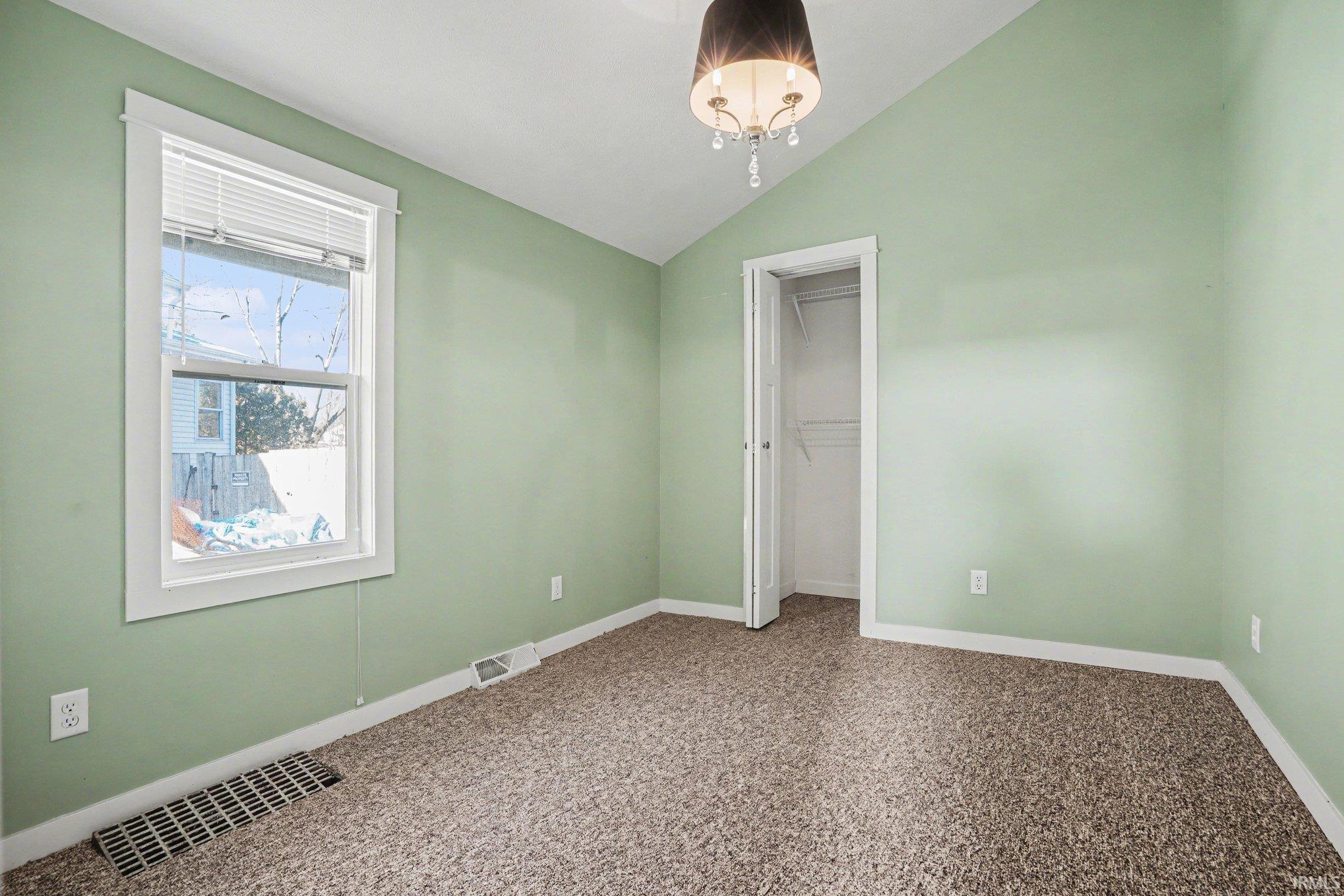 Unfurnished bedroom featuring lofted ceiling and a closet