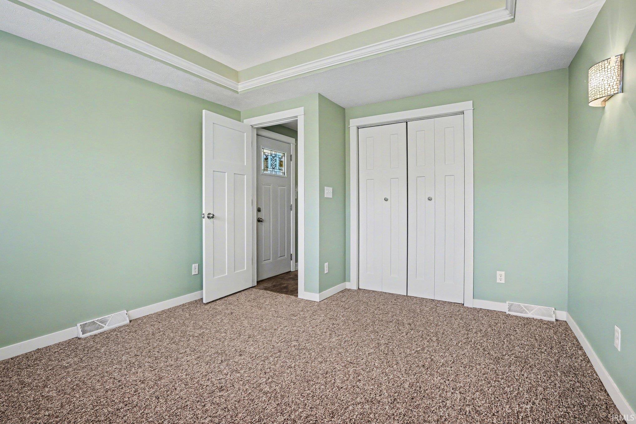 Unfurnished bedroom featuring dark carpet, a tray ceiling, and a closet