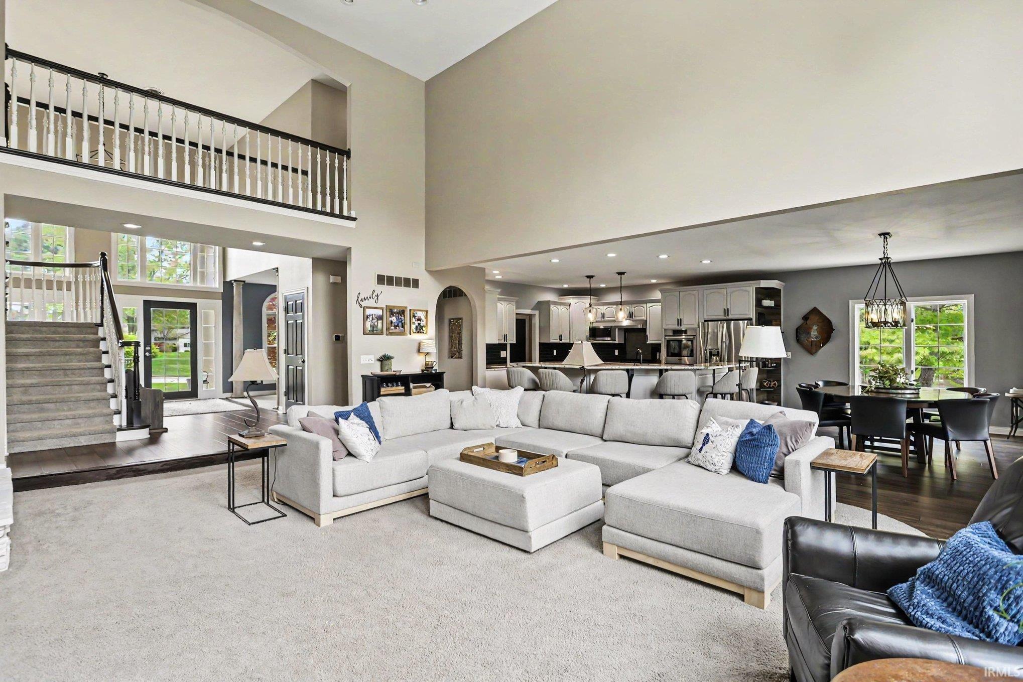Open concept living area featuring a two-story ceiling, a staircase with dark wood-finish treads and white risers, and an upper-level balcony with white balusters