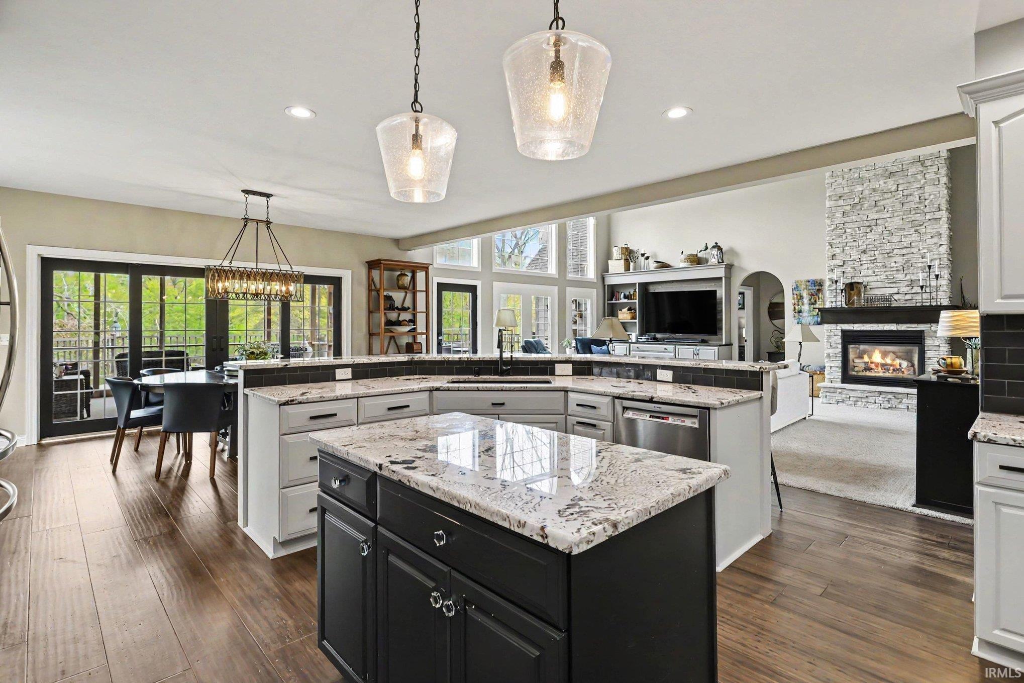 Spacious kitchen featuring a large central island with a contrasting base, light-toned perimeter cabinetry, and stone countertops