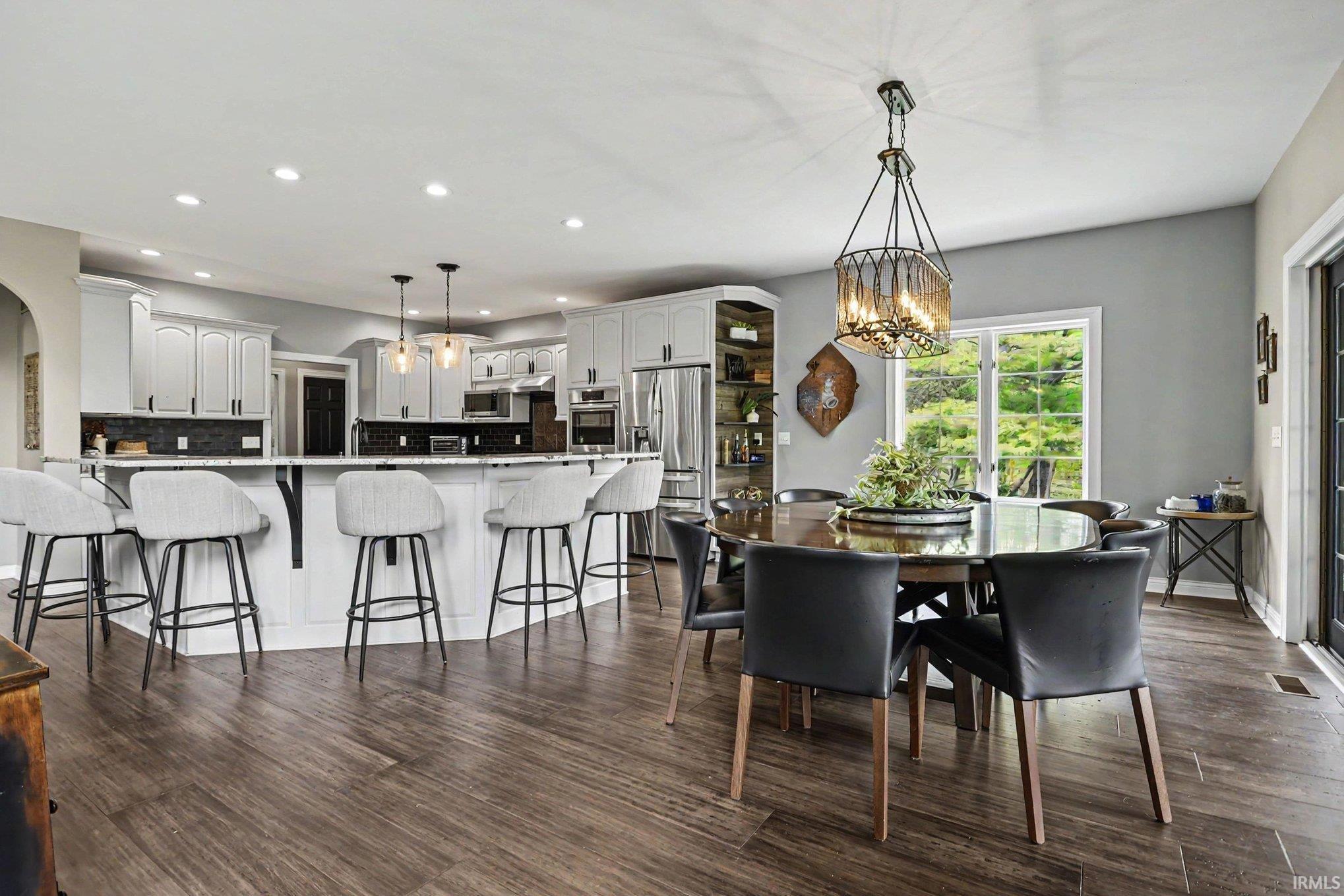 Open-concept kitchen and dining area featuring wood-finish flooring, recessed lighting, and a white kitchen island with counter seating