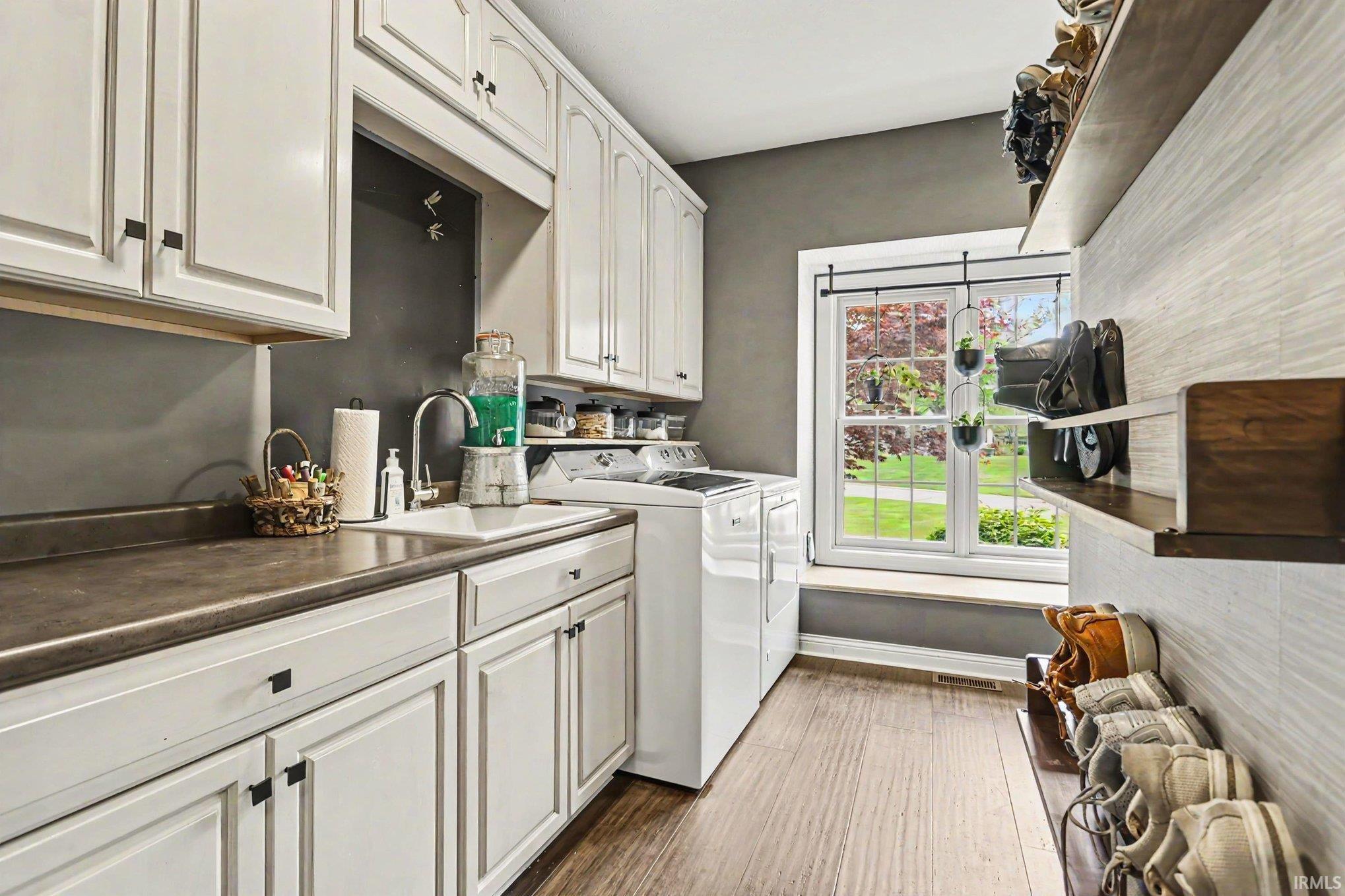Laundry area featuring white cabinetry, a sink with a stainless steel faucet, and a window with a sill