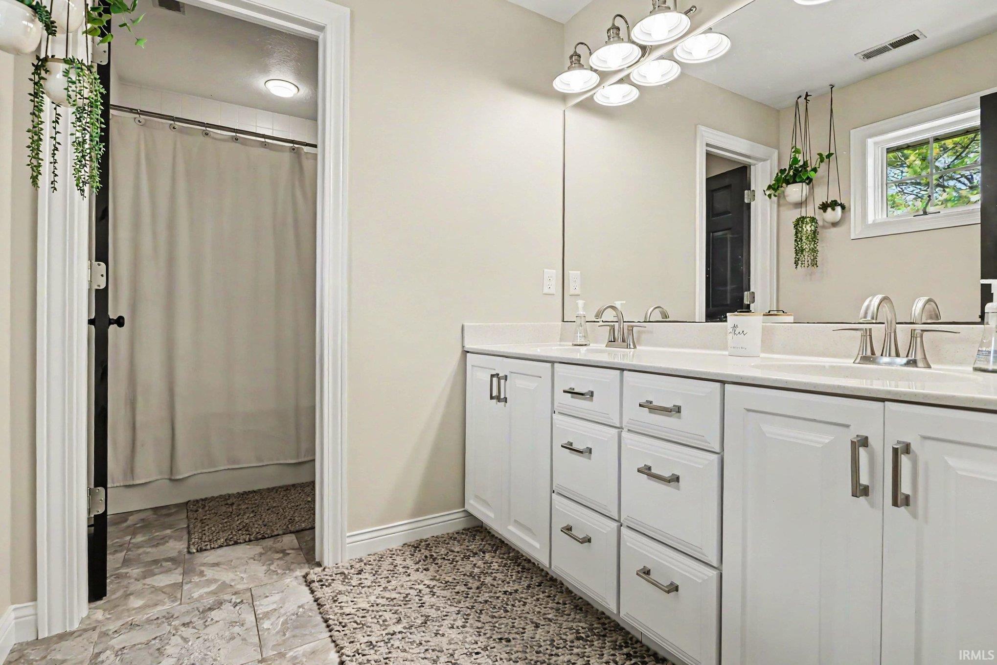 Double vanity with white cabinetry, brushed nickel hardware, and a light-colored countertop