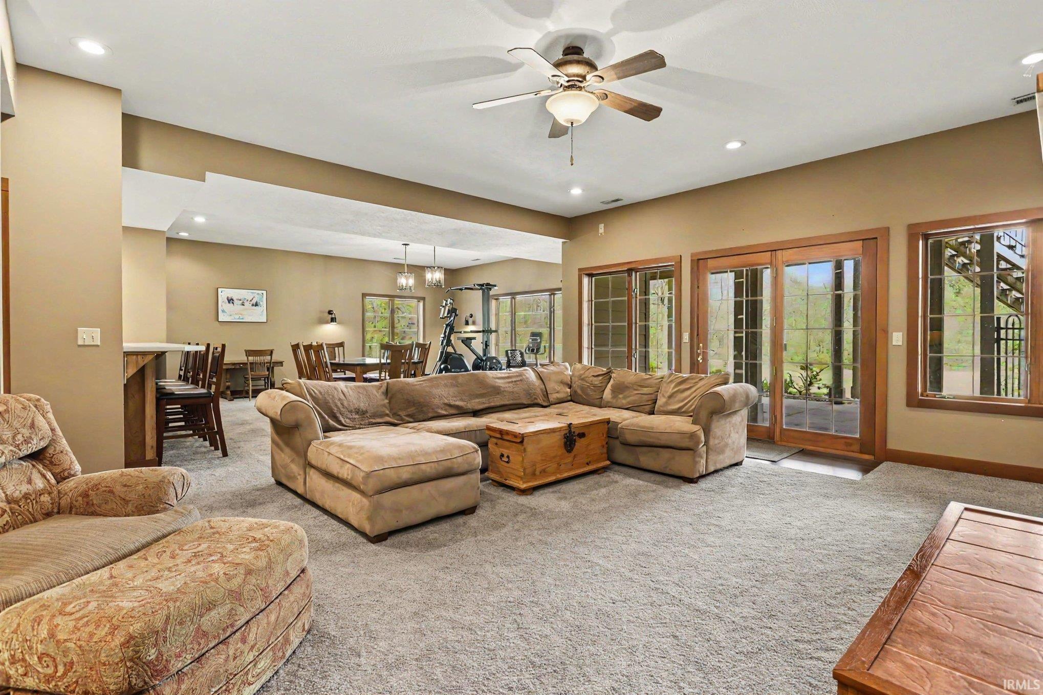 Spacious living area featuring neutral carpeting, recessed lighting, and a ceiling fan