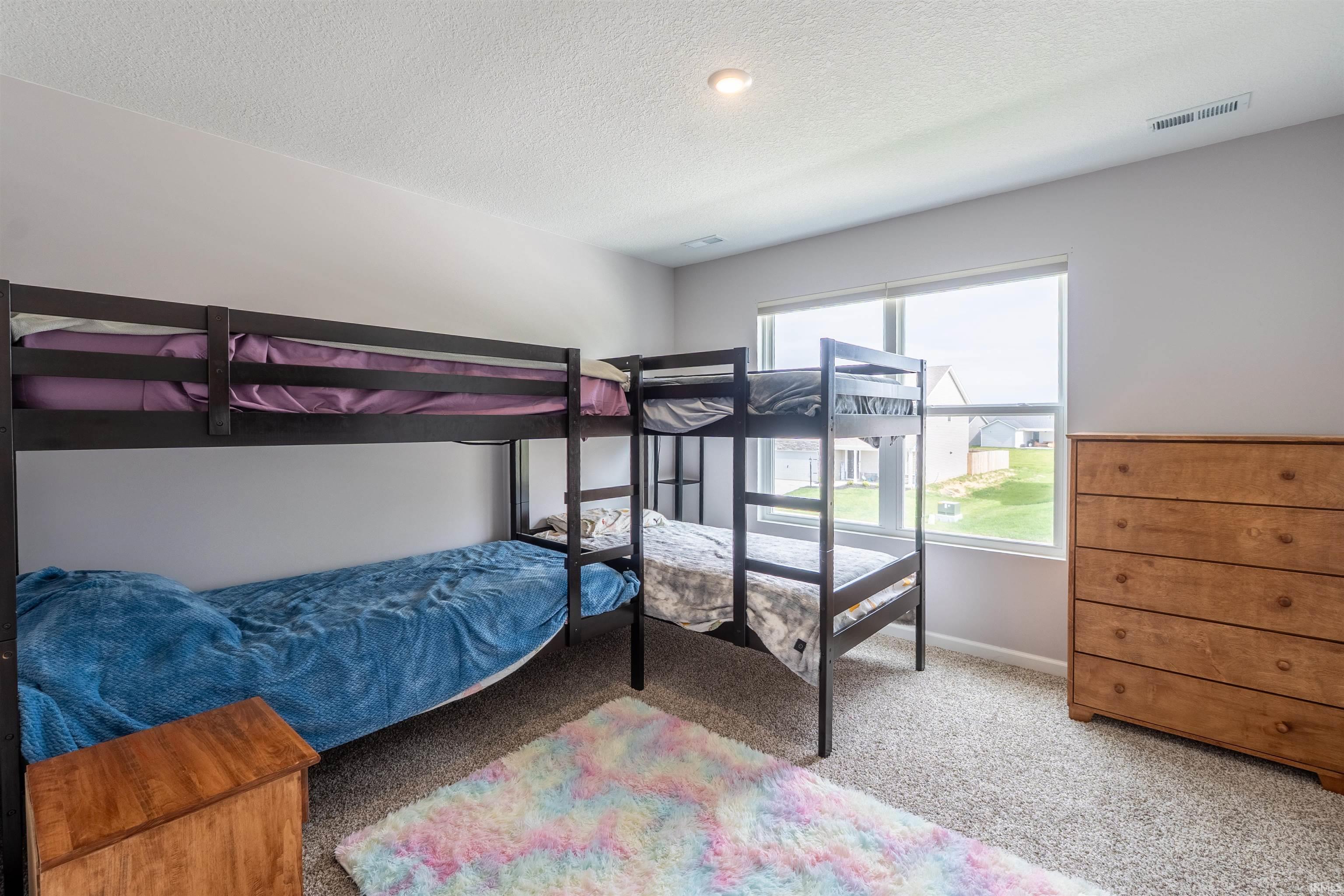Neutral-toned bedroom featuring carpet flooring, a large window, and recessed lighting