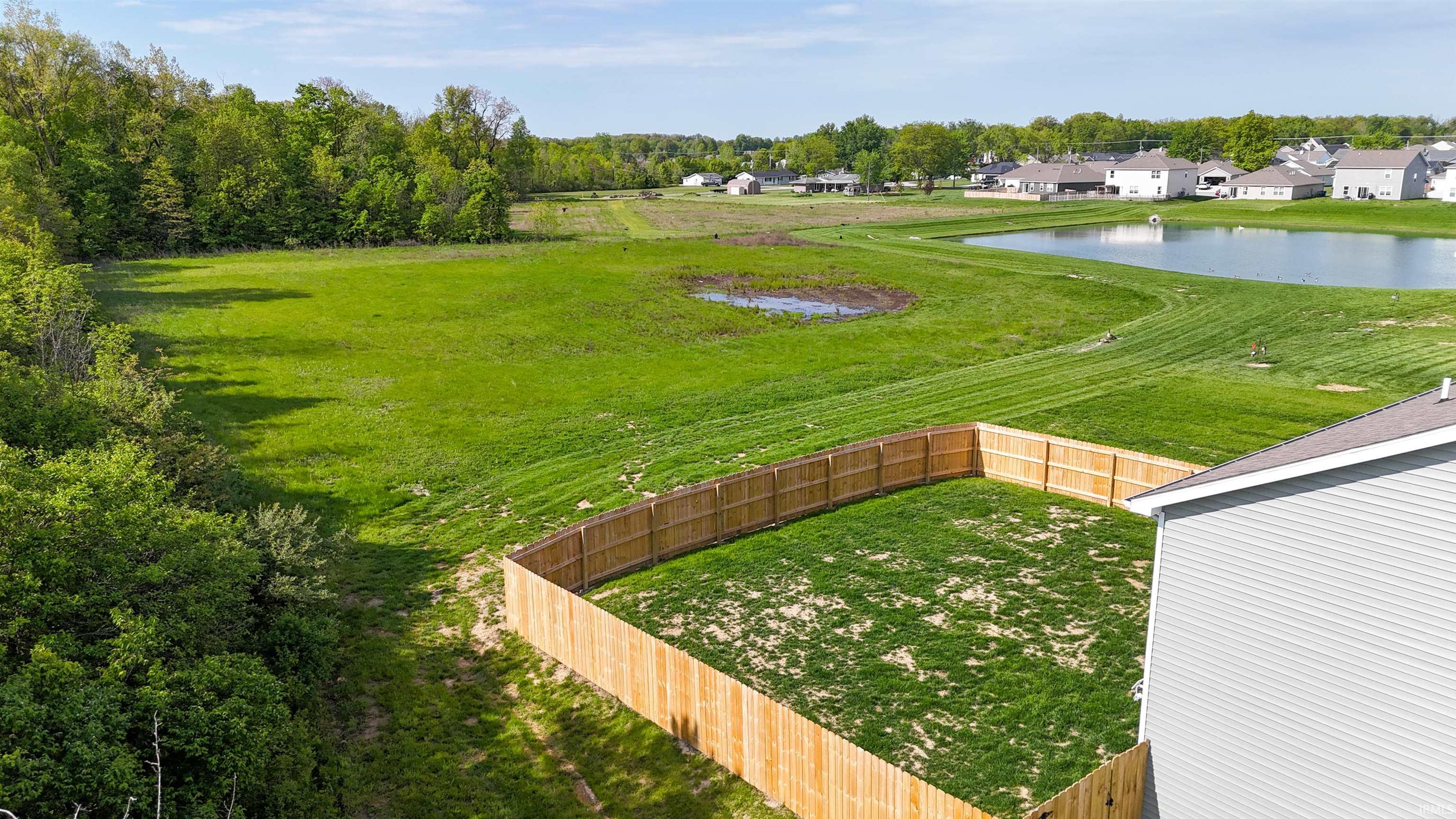 Fenced backyard featuring green lawn and a natural wood privacy fence