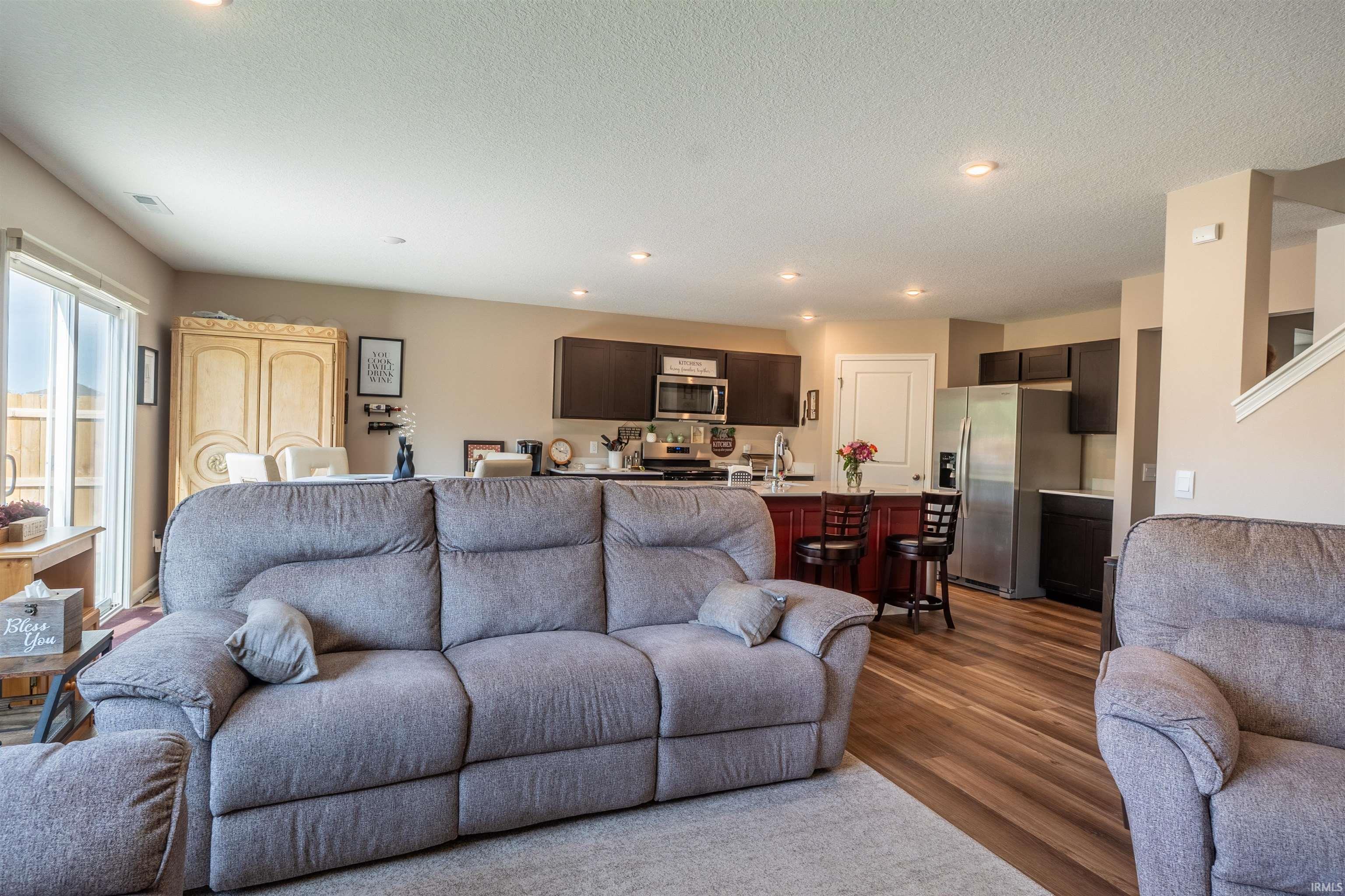 Open-concept living space featuring wood-finish flooring, recessed lighting, and a sliding glass door
