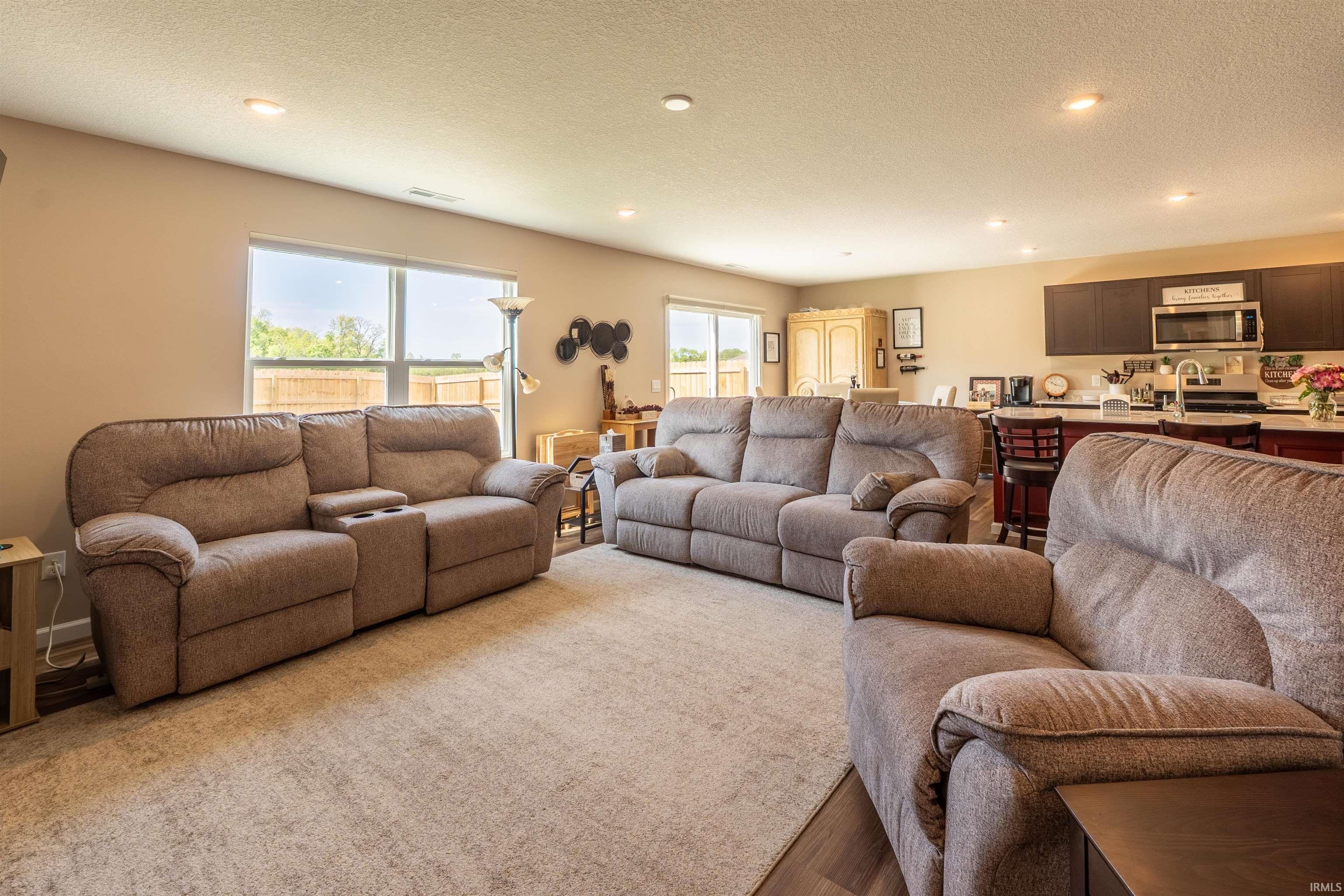 Open-concept living area featuring recessed lighting, a large rear-facing window, and wood-finish flooring