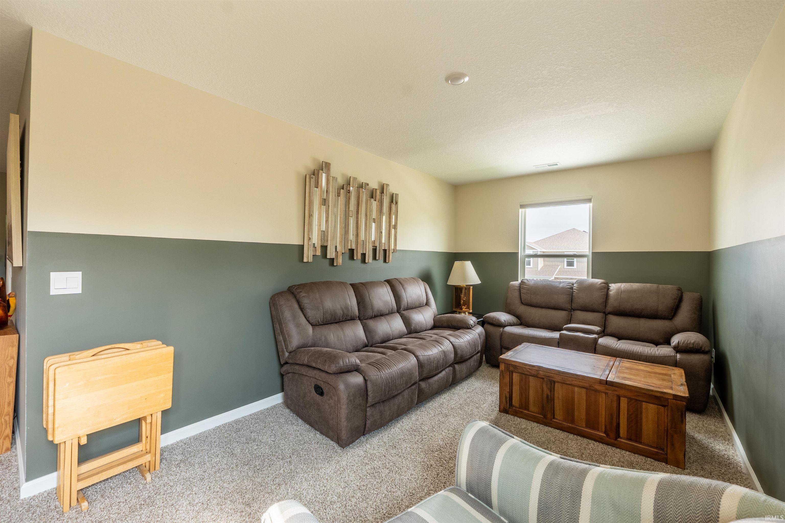 Spacious interior room featuring a neutral-toned carpet, a window, and a two-tone wall finish