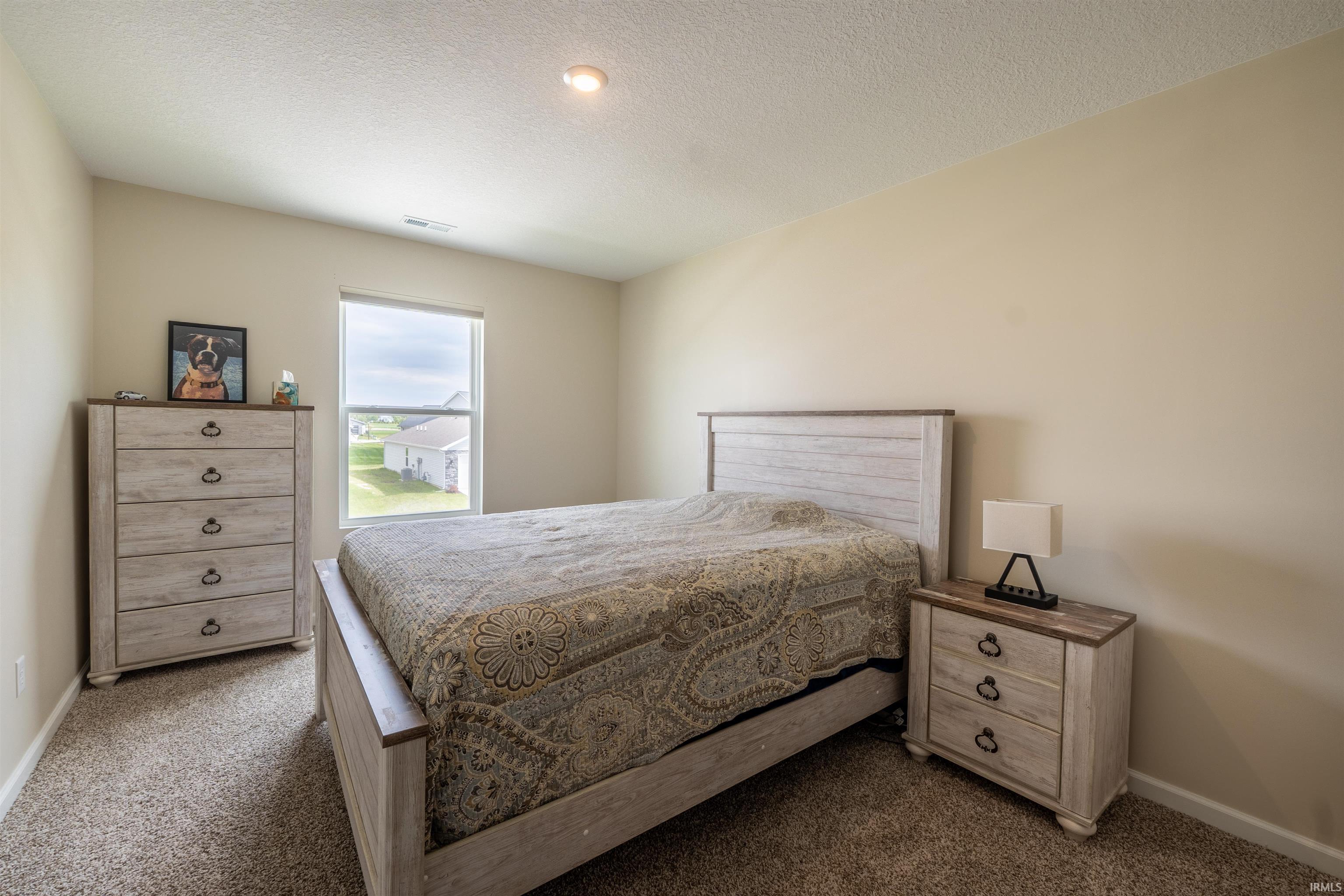 Carpeted bedroom with a single window, recessed ceiling lighting, and neutral wall tones