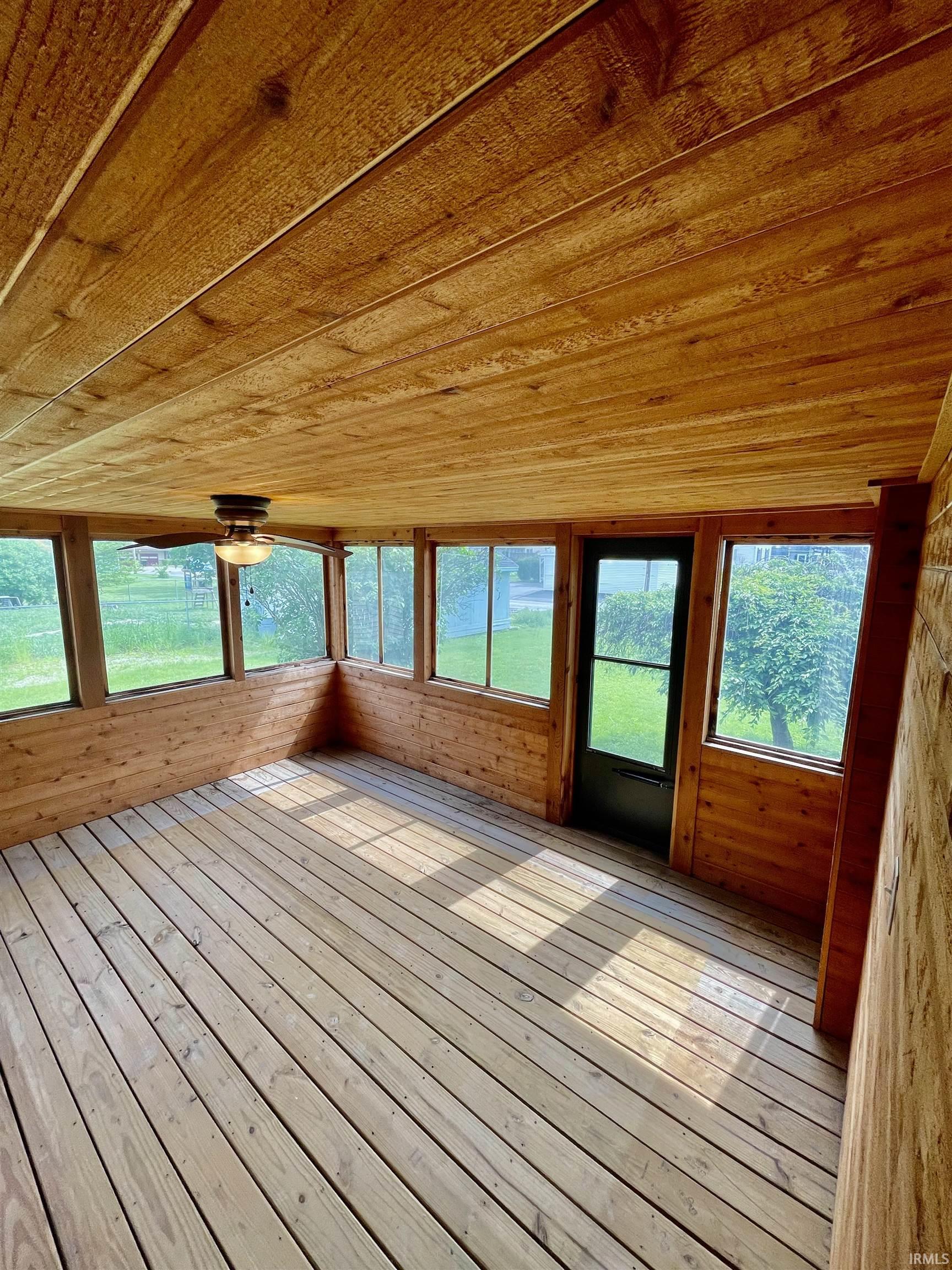 Screened-in porch featuring wood plank flooring, wood panel walls, and a wood plank ceiling