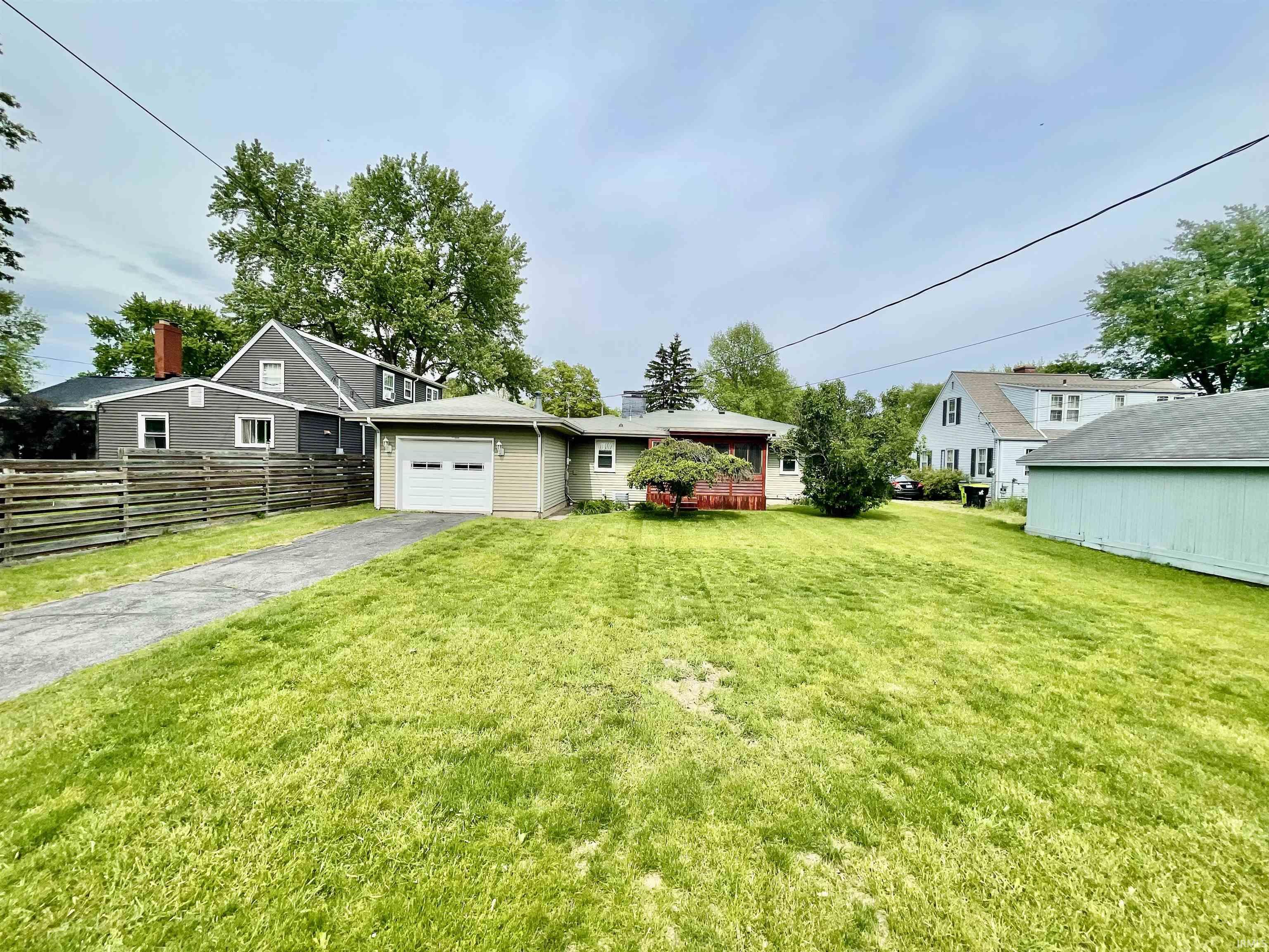 Spacious green lawn with a paved driveway and detached garage
