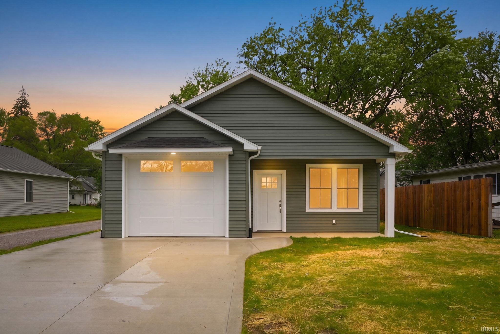 Modern ranch-style home! Exterior featuring a covered porch, attached garage with upper window panels, and a newly laid concrete driveway.