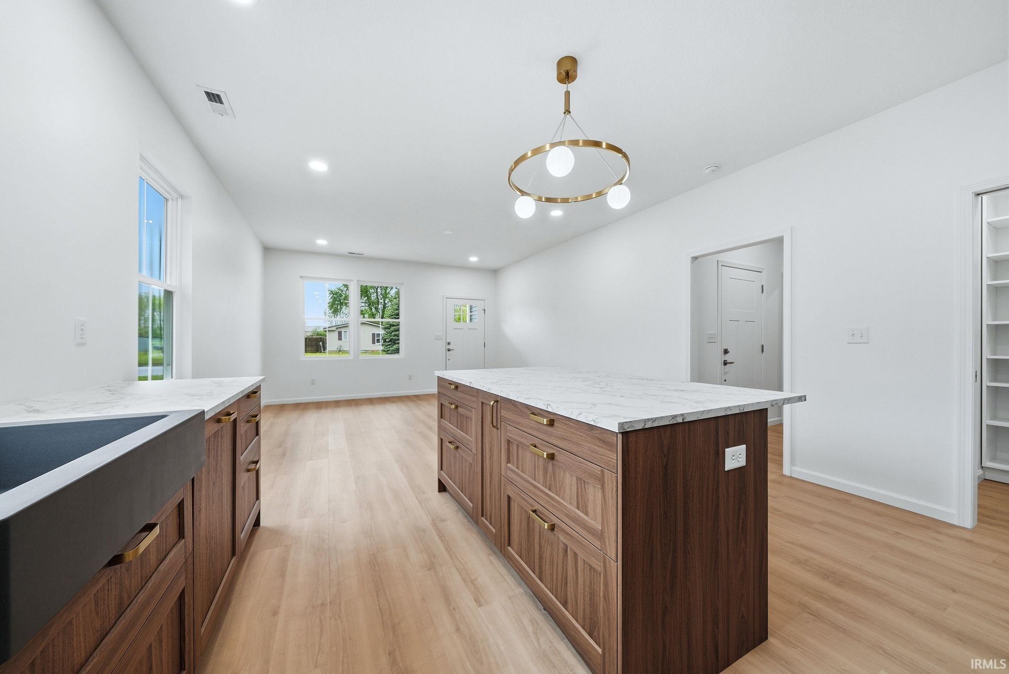 Kitchen featuring a large island with wood-finish cabinetry, brass hardware, and a black farmhouse sink