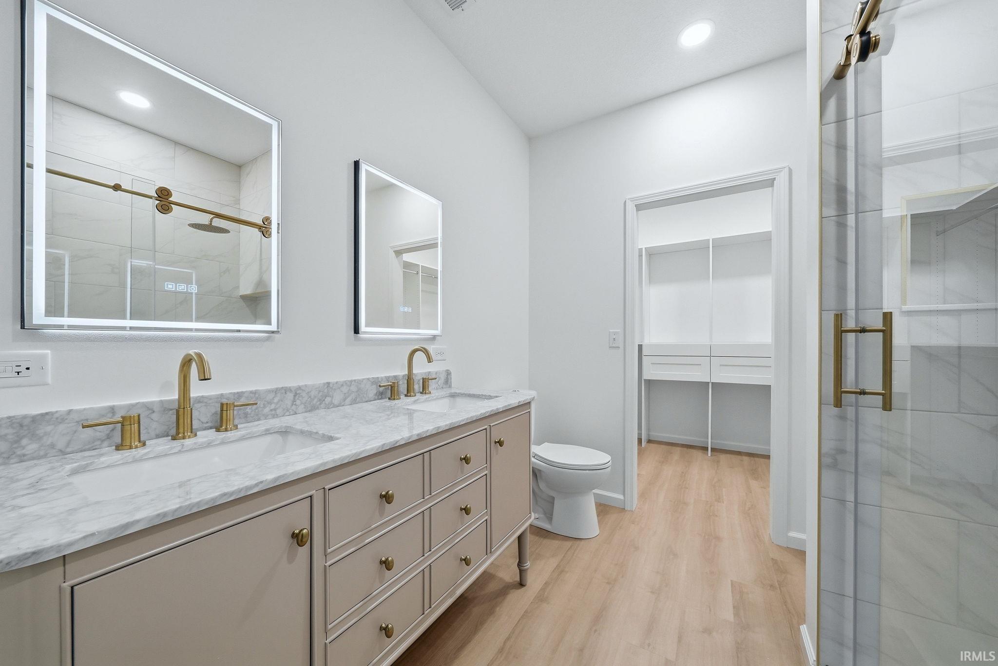 Bathroom featuring a light-toned dual vanity, individual Smart LED illuminated mirrors, and gold-finish fixtures