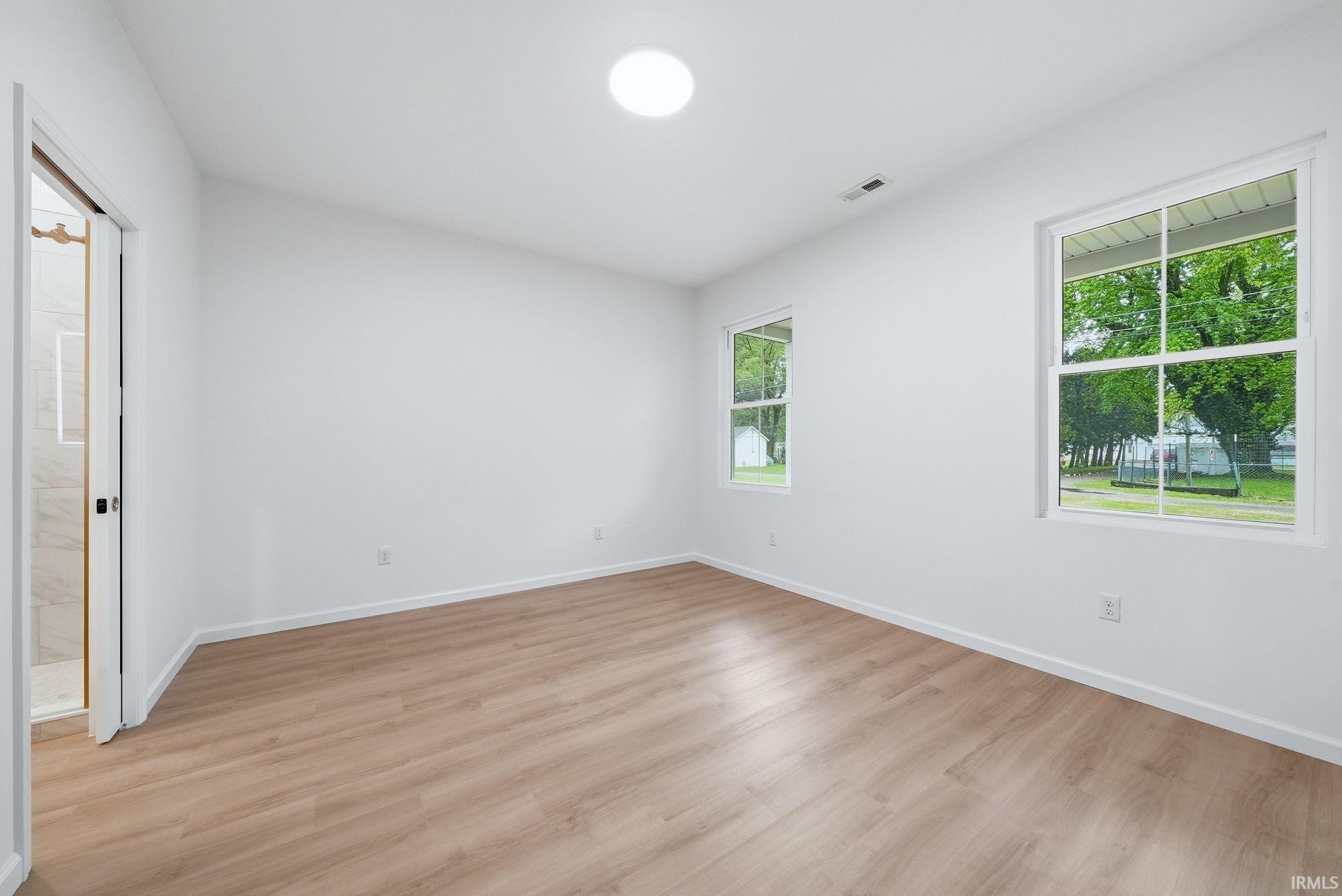 Bright interior space featuring wood-finish flooring, white walls, and two multi-pane windows