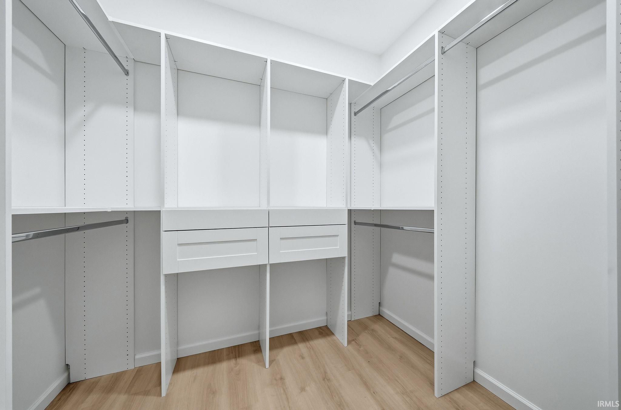 Custom white built-in closet system featuring multiple shelving units, hanging rods, and integrated drawer storage