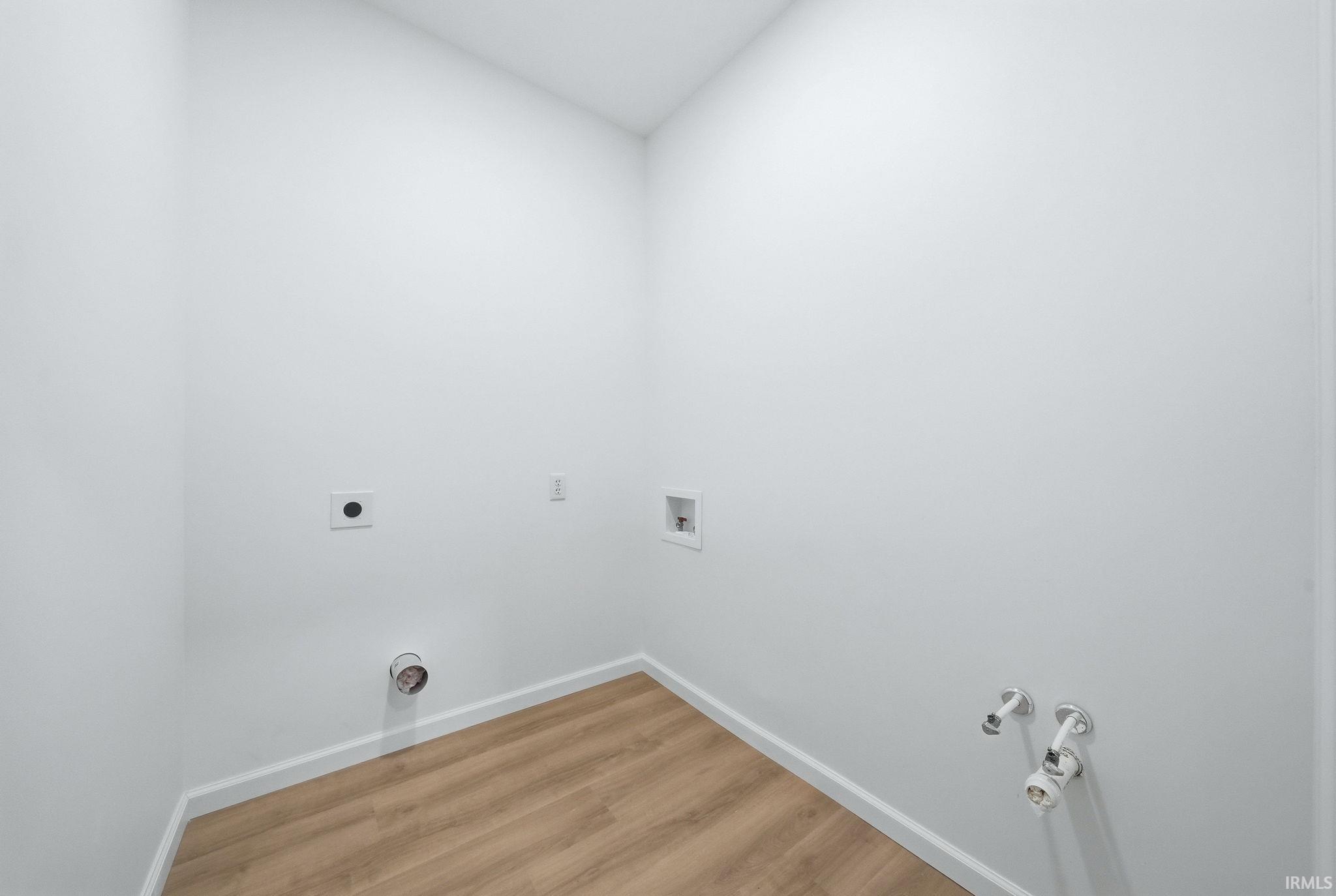 Dedicated utility space featuring wood-finish flooring and crisp white walls
