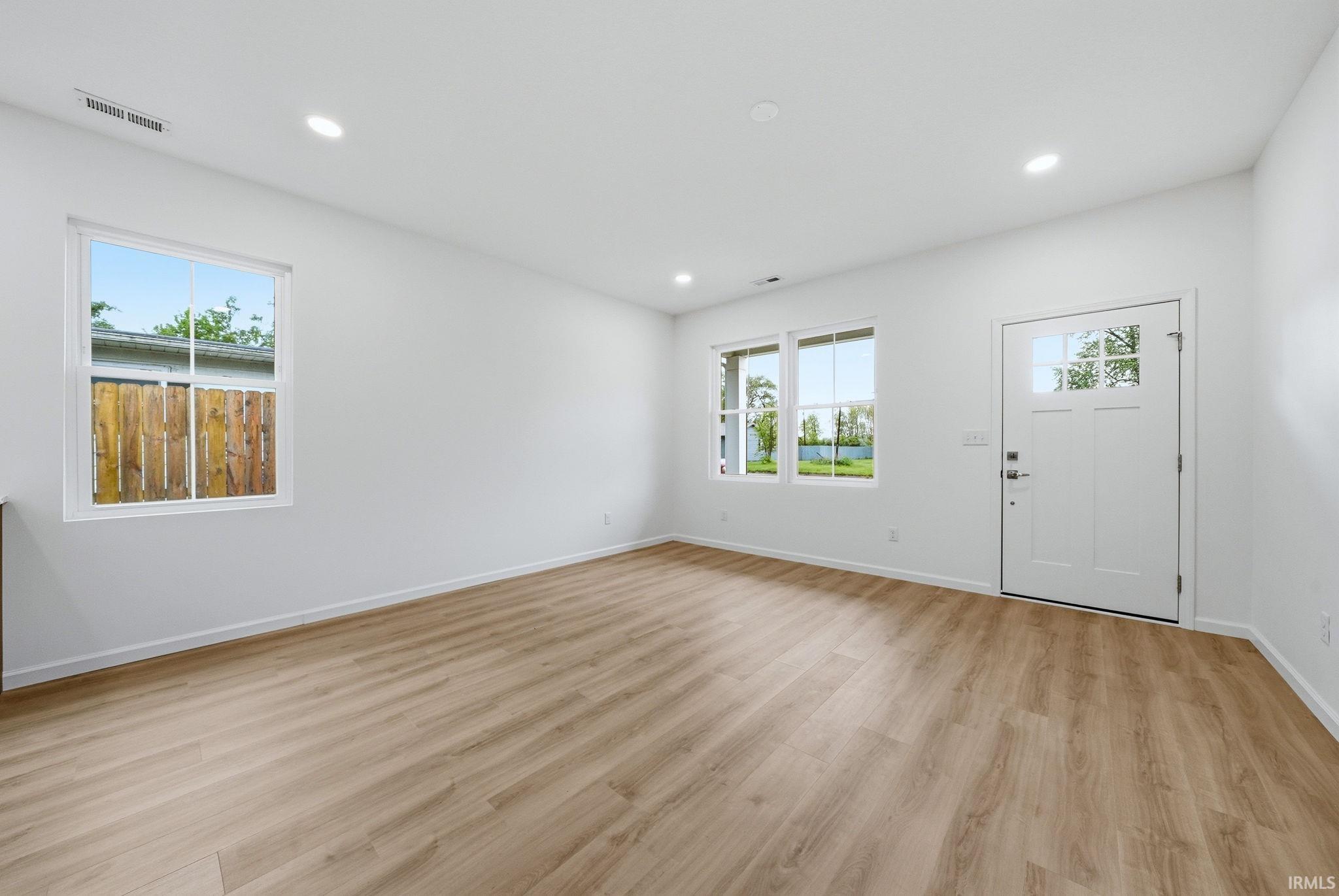 Open-concept living space featuring wood-finish flooring, recessed lighting, and bright white walls