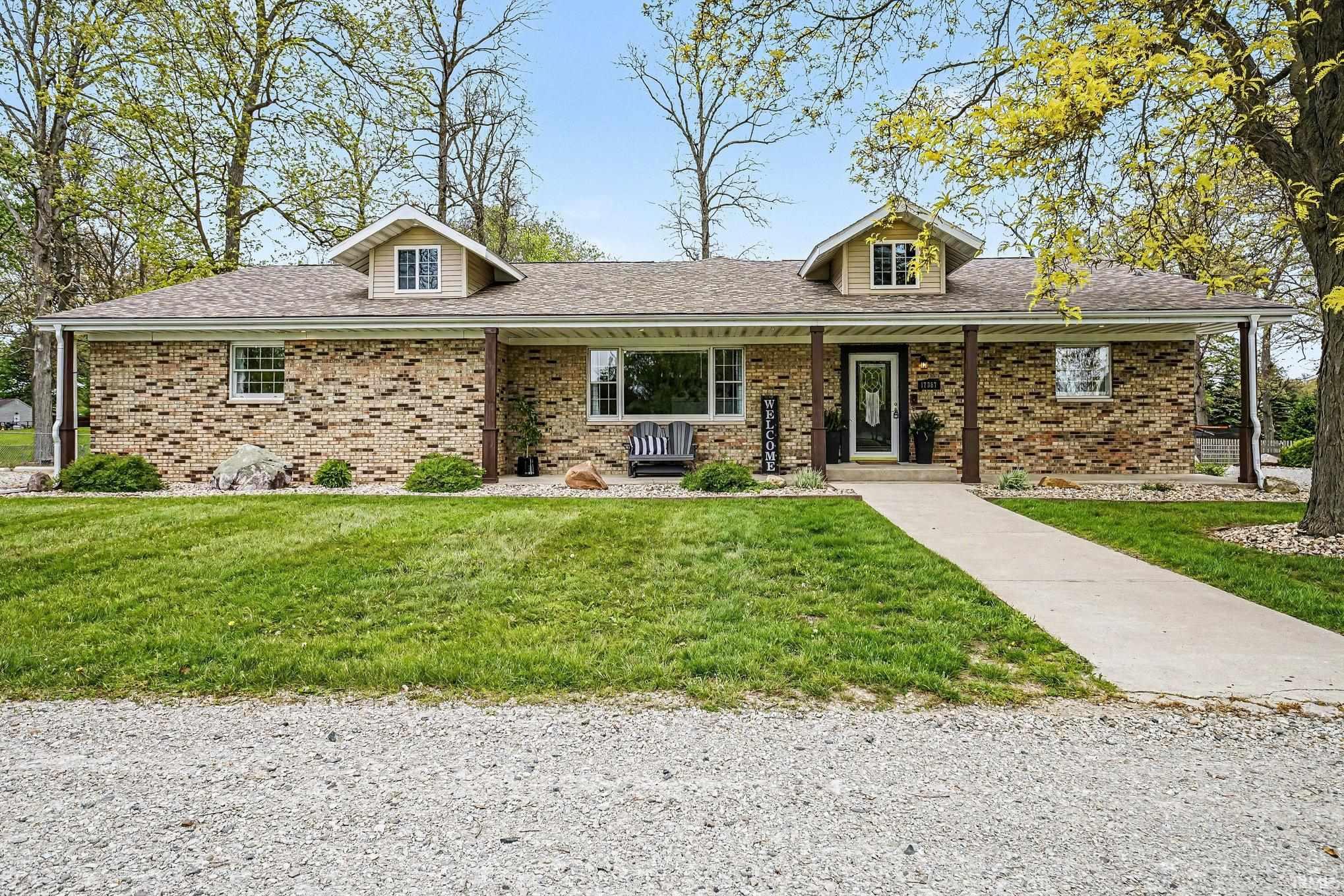 Ranch-style residence featuring a brick facade with stone accents and a covered front porch