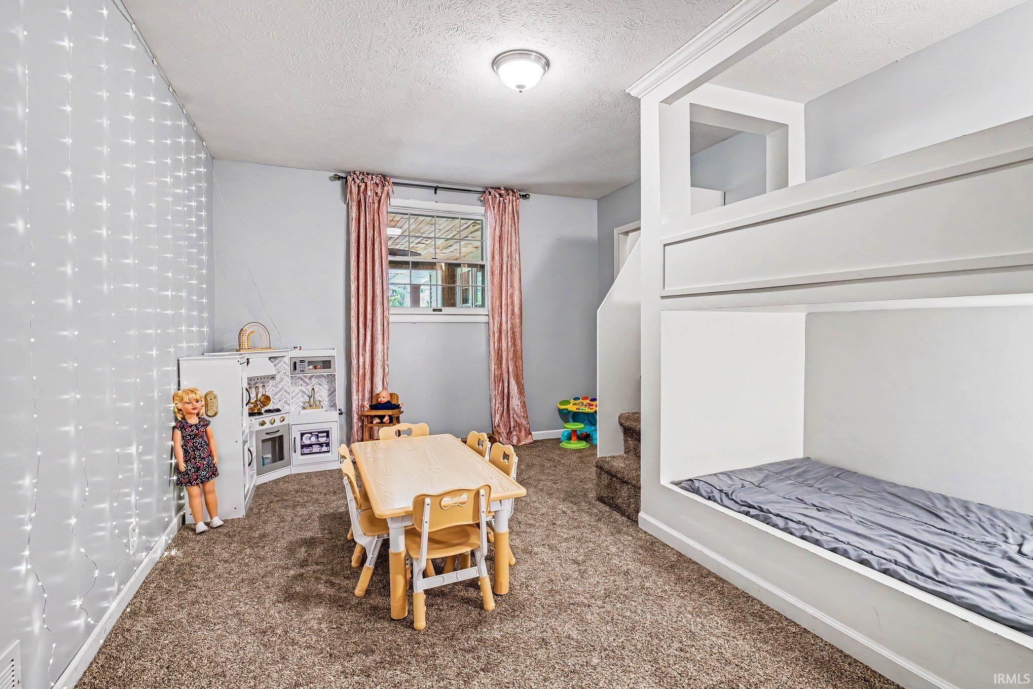 Built-in bunk bed structure with crown molding details, carpeted flooring, and a single window with curtain rods