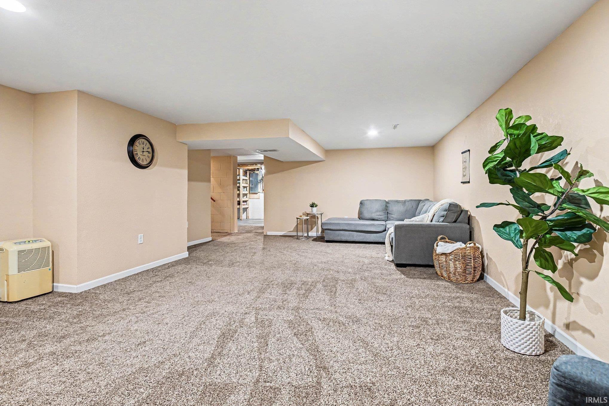 Spacious room featuring neutral carpeting, light-toned walls, recessed lighting, and a visible hallway entry