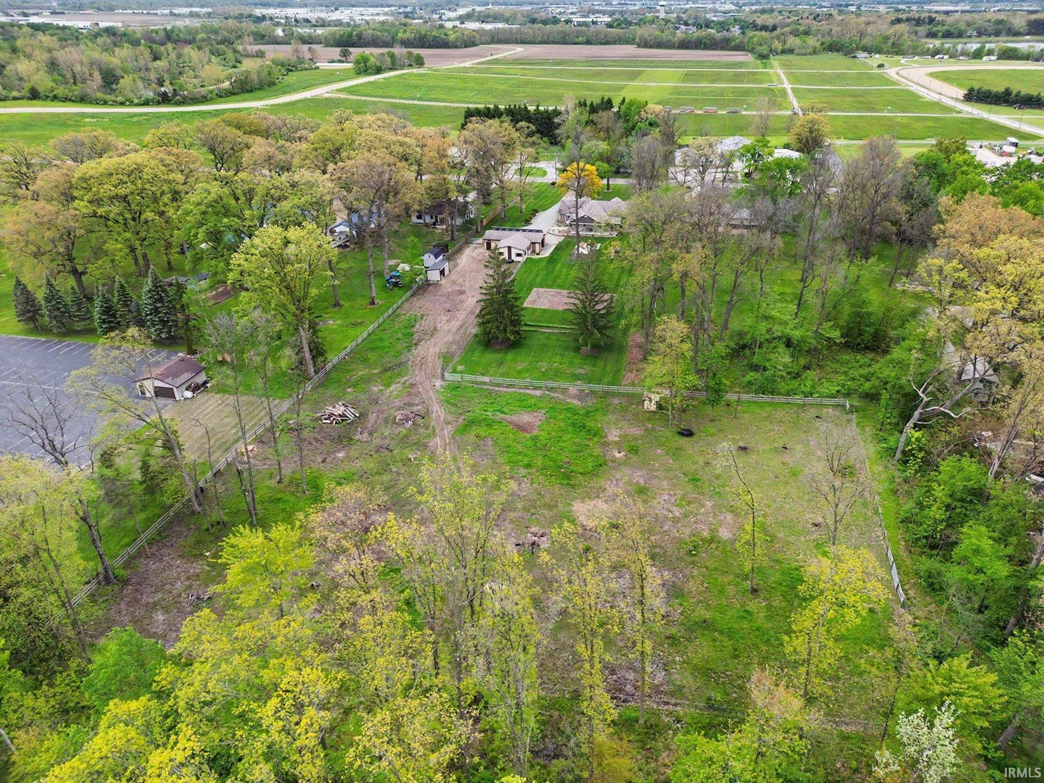 Expansive property featuring a mix of mature trees, open green spaces, and an asphalt paved area