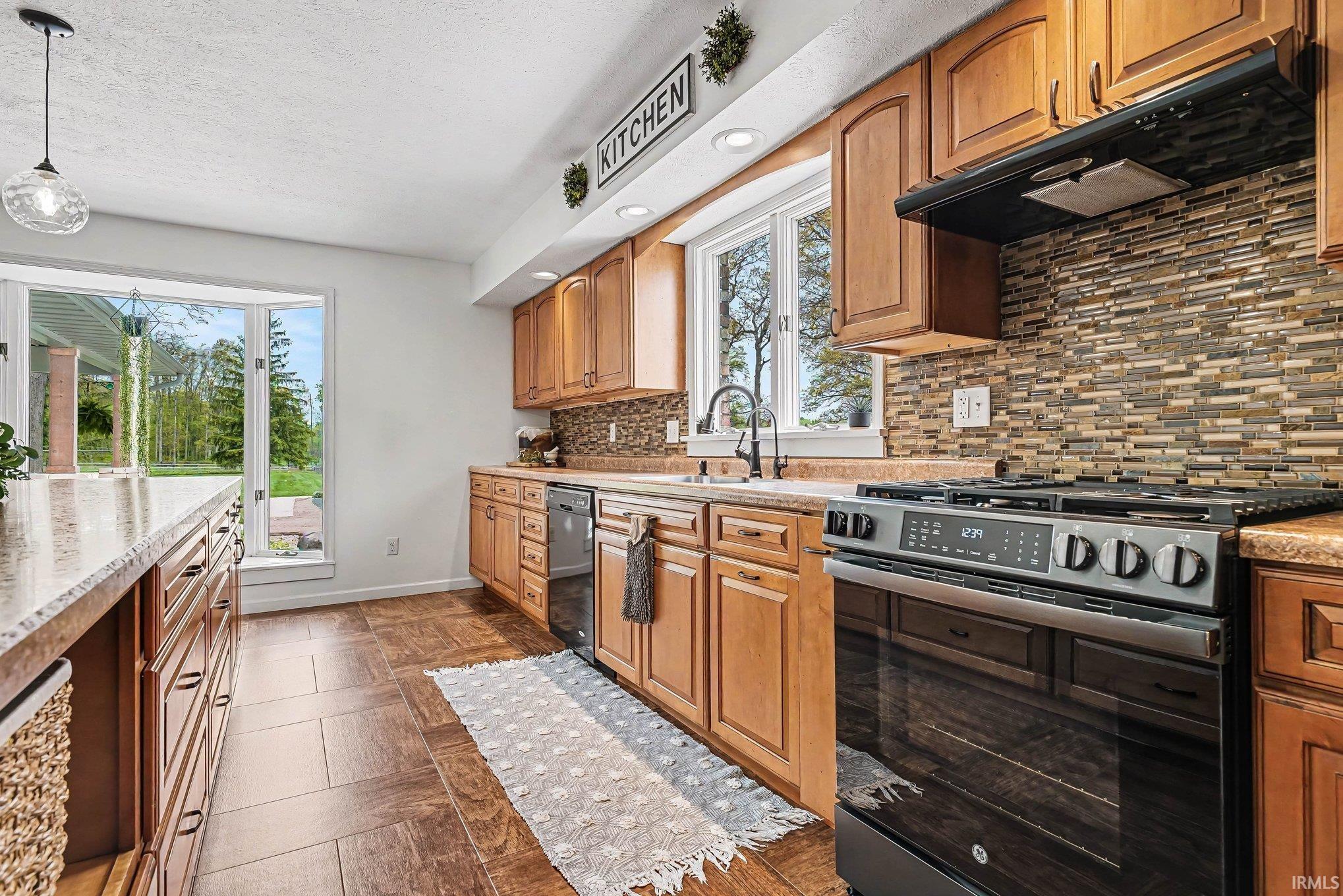 Modern kitchen featuring wood-finish cabinetry, stainless steel range, and a mosaic tile backsplash