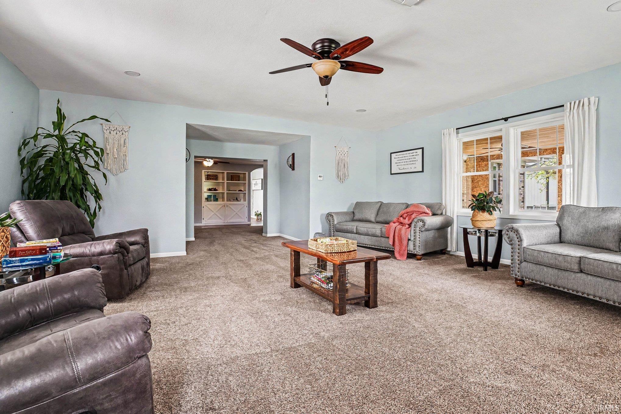 Spacious living area featuring light-colored walls and plush carpeting