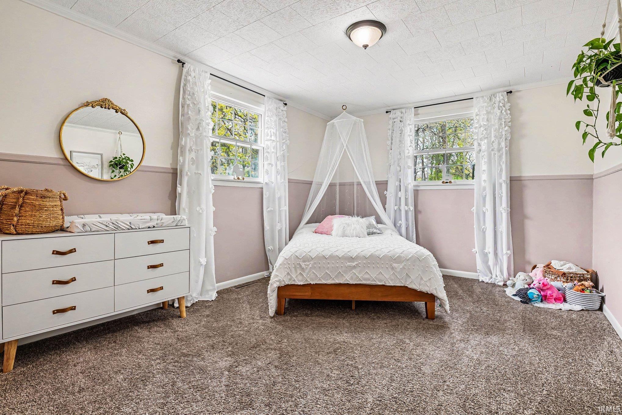 Carpeted room with a textured ceiling, two double-hung windows, and a semi-flush mount ceiling light fixture