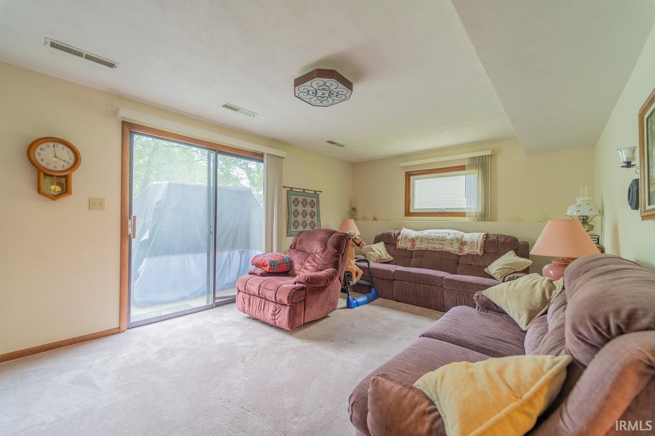 Carpeted interior space featuring a large sliding glass door, a horizontal window with blinds, and recessed lighting